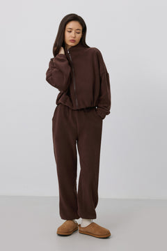 Frontalaufnahme des Models in dem dunkelbraunen Fleece-Set, kombiniert mit gemütlichen Hausschuhen