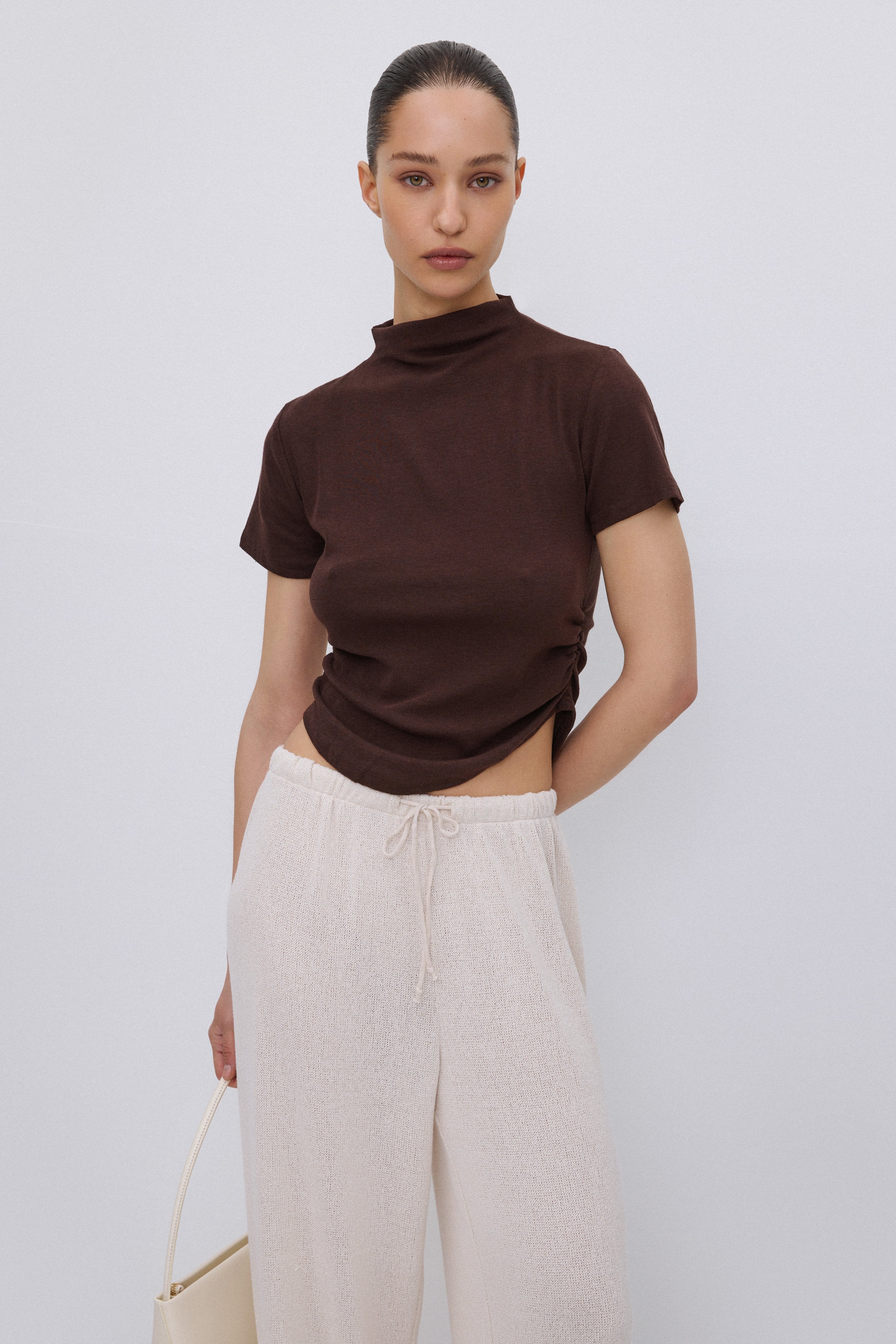 Frontalansicht des dunkelbraunen Damen T-Shirts mit Stehkragen und modischer Taillenraffung.