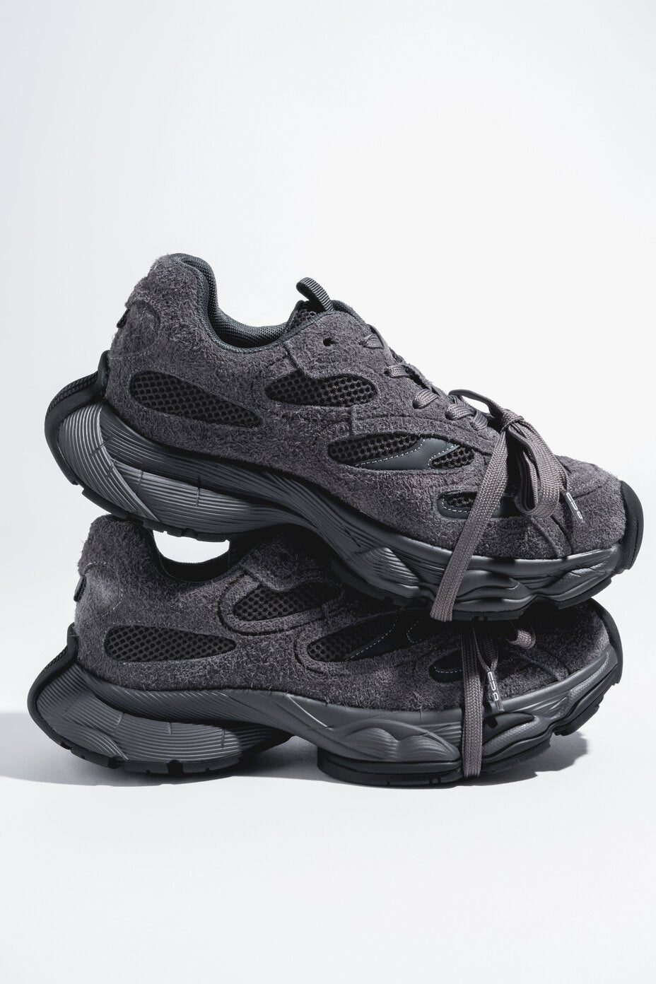 Übereinander gestapelte dunkelgraue Chunky-Sneaker mit strukturierter Oberfläche, Mesh-Einsätzen und massiver Plateausohle