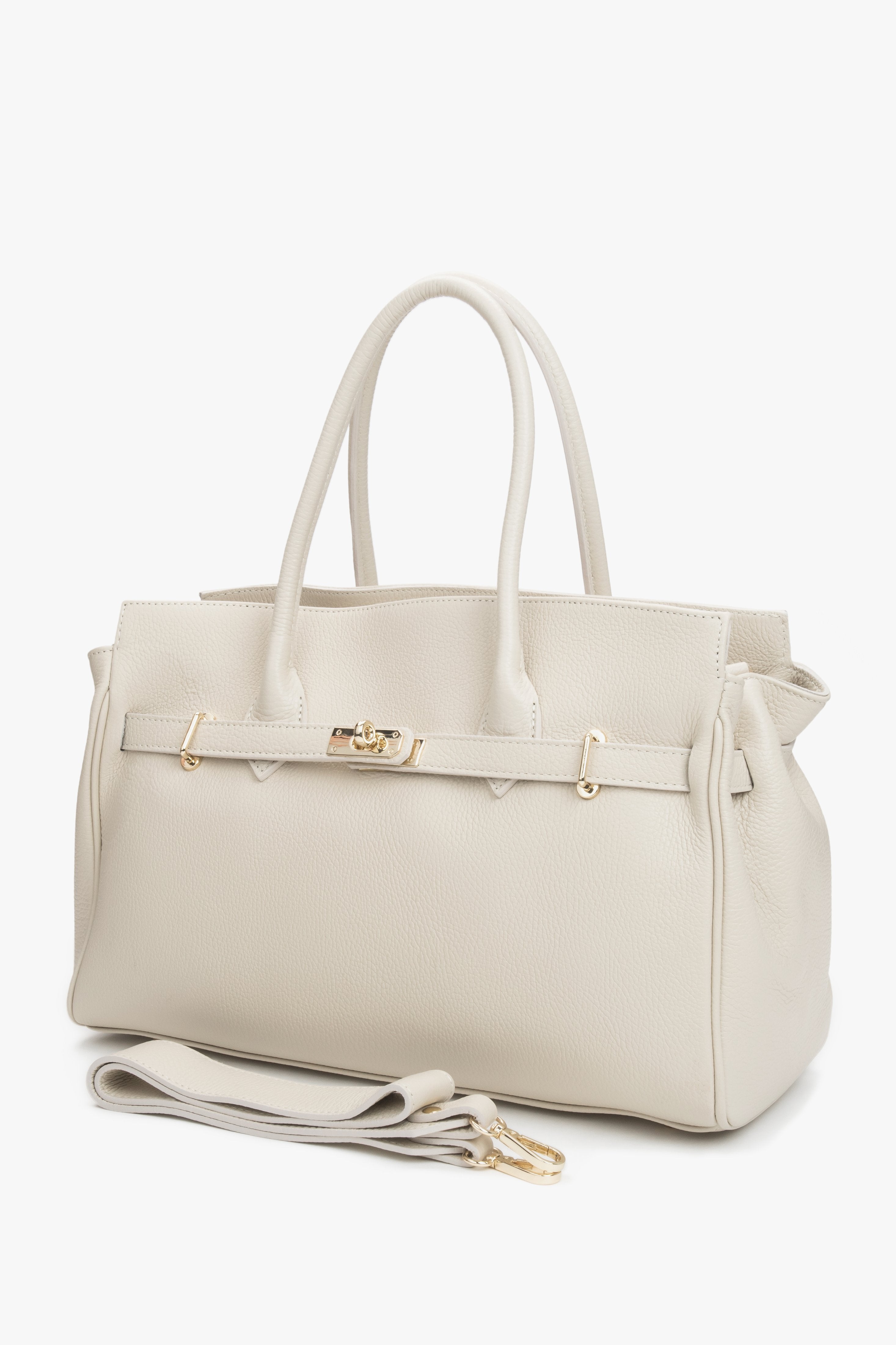 Schräge Seitenansicht der milchbeigen Ledertasche mit Tragegriff und Schulterriemen.