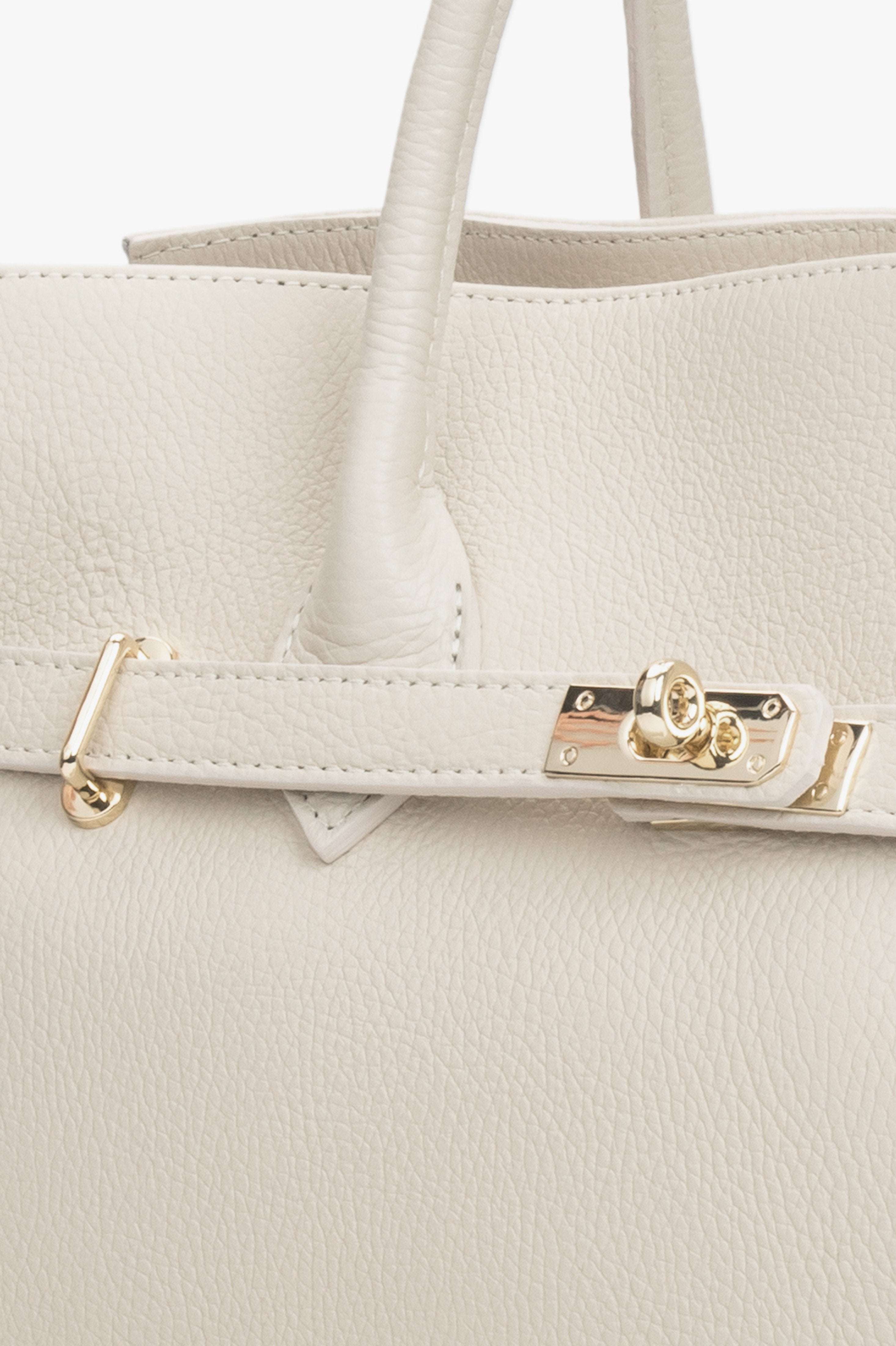 Nahaufnahme der eleganten Beschläge an der milchbeigen Premium-Ledertasche.