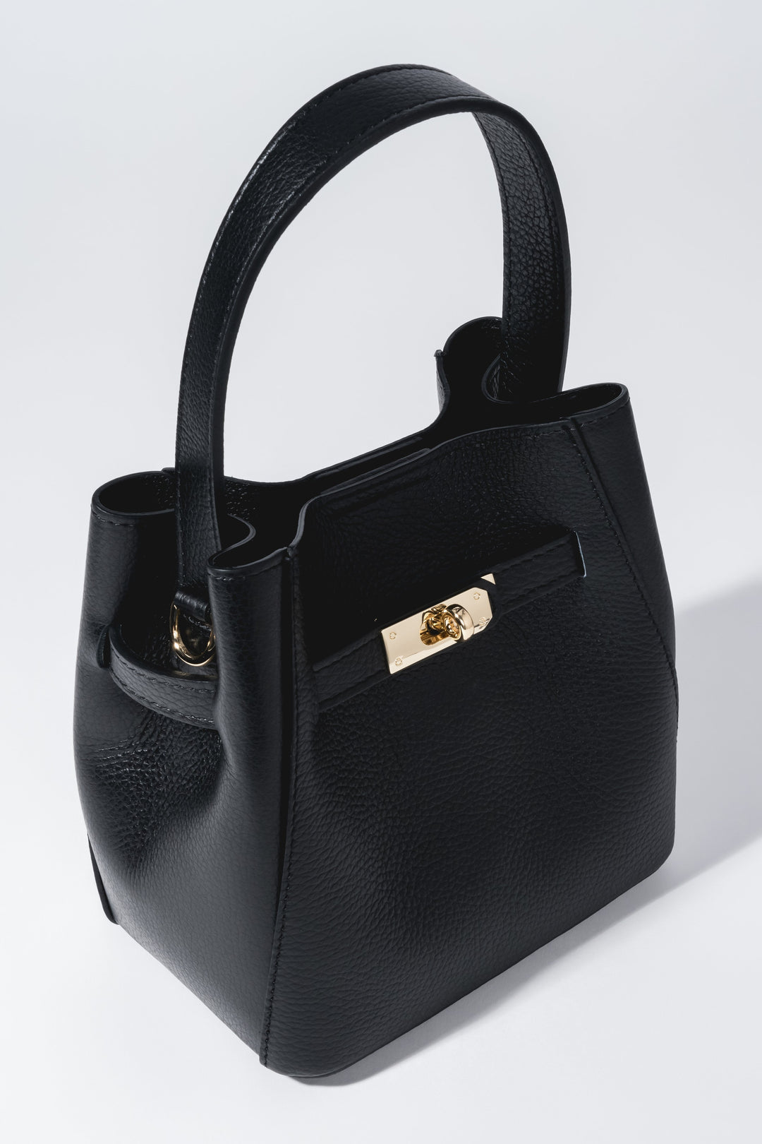 Frontale Schrägansicht der kompakten schwarzen Leder-Henkeltasche mit goldenem Druckverschluss und genarbter Struktur 