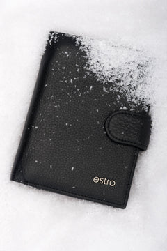 Frontalansicht der handlichen schwarzen Herren-Geldbörse aus Echtleder mit Druckknopfverschluss im Schnee.