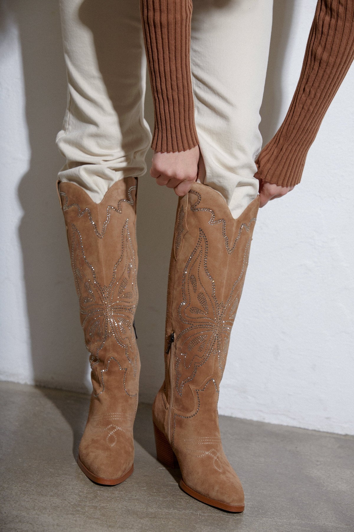 Model passt den Schaft der hellbeigen Cowboystiefel im Stehen an