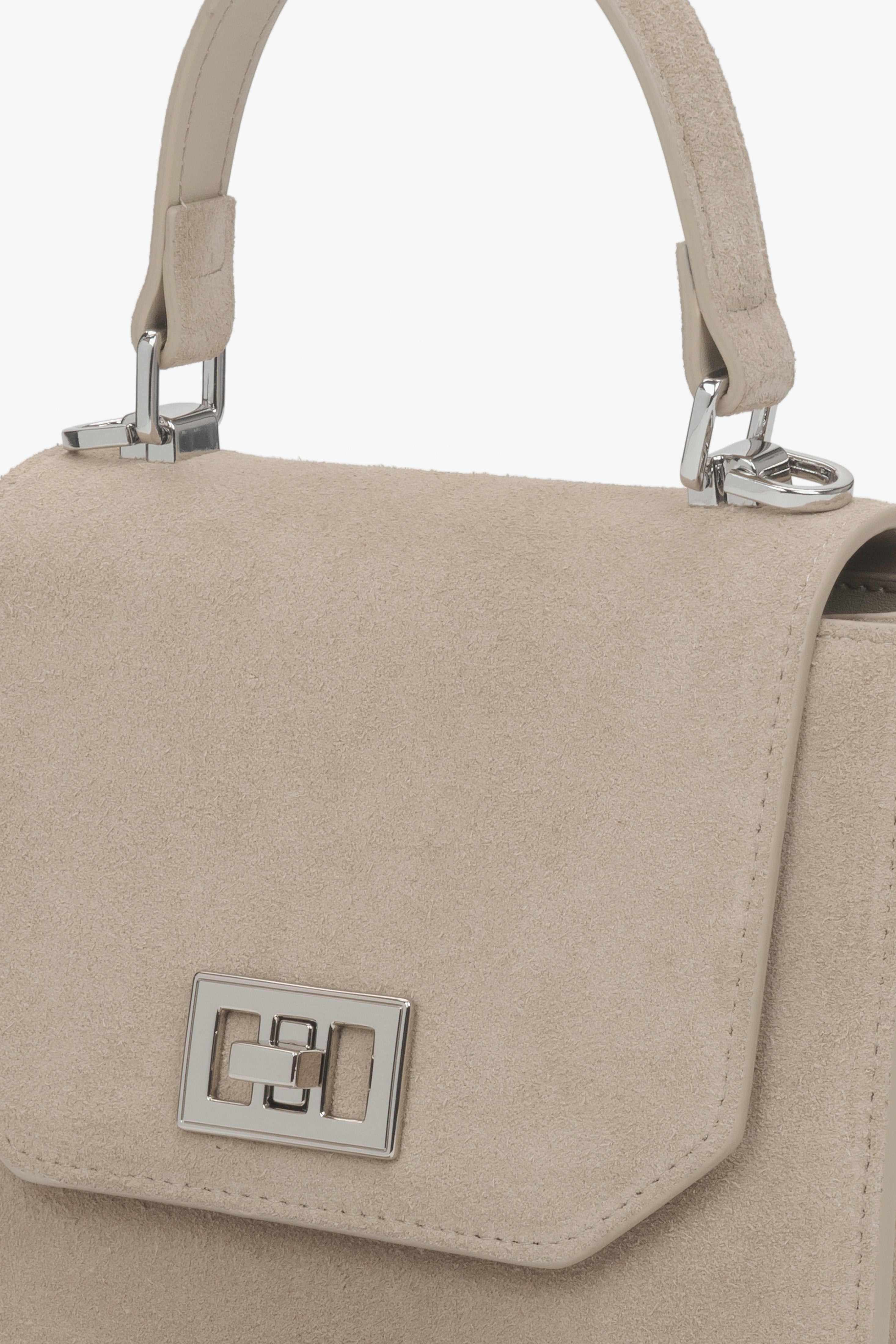 Detailaufnahme der Lederstruktur und des Schnallenverschlusses der hellbeigen Tasche.
