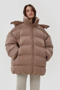 Model präsentiert die offene hellbeige Oversize-Pufferjacke mit hohem Kragen