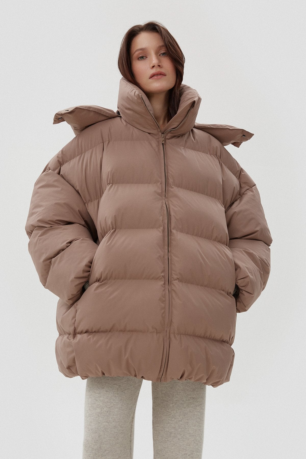 Model präsentiert die offene hellbeige Oversize-Pufferjacke mit hohem Kragen