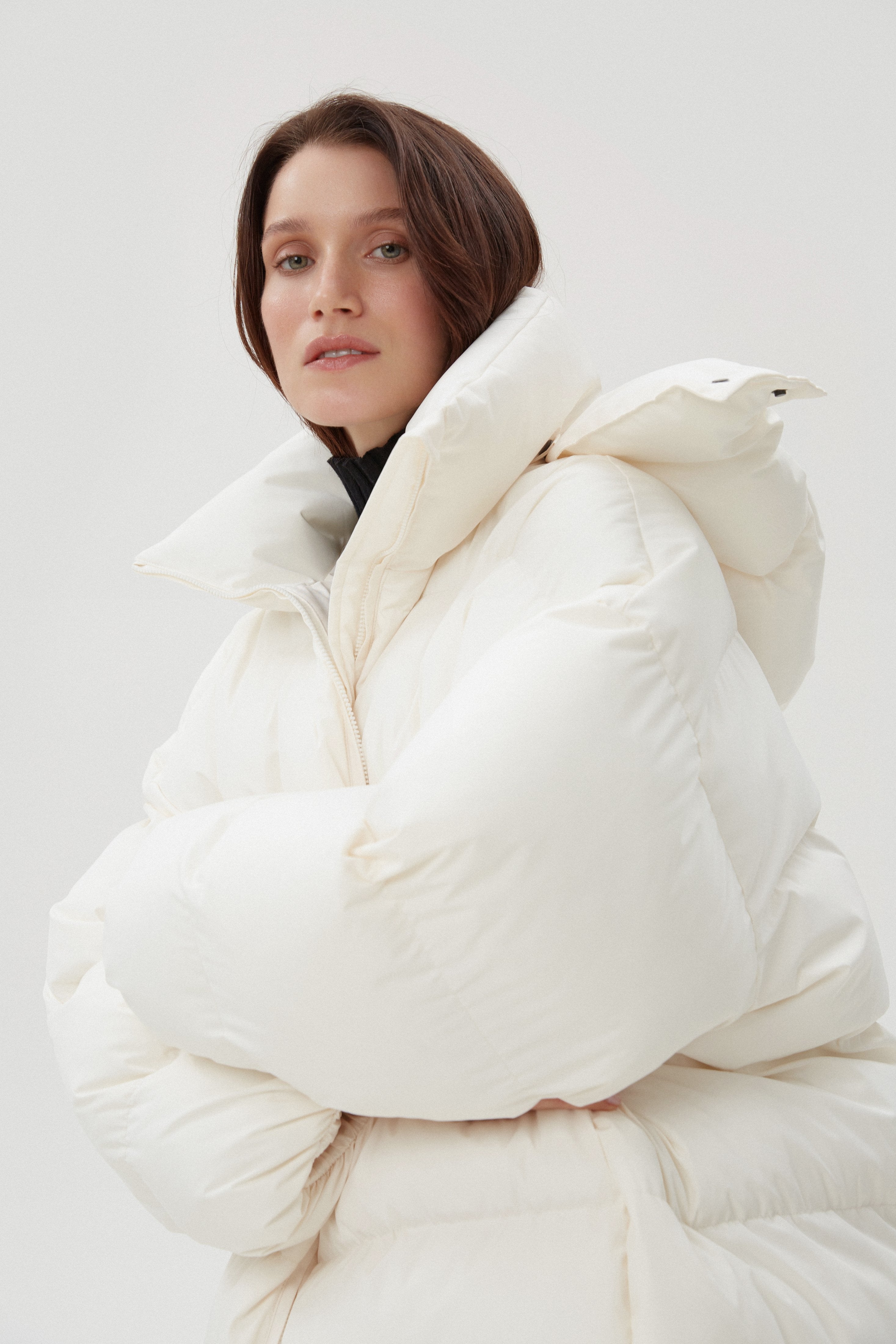 Seitliches Profil der hellbeigen Oversize-Pufferjacke mit geschlossener Kapuze