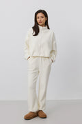 Frontalansicht des Models im hellbeigen Damen-Fleece-Set mit entspanntem Loose Fit und braunen Hausschuhen