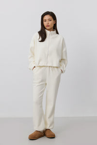 Frontalansicht des Models im hellbeigen Damen-Fleece-Set mit entspanntem Loose Fit und braunen Hausschuhen