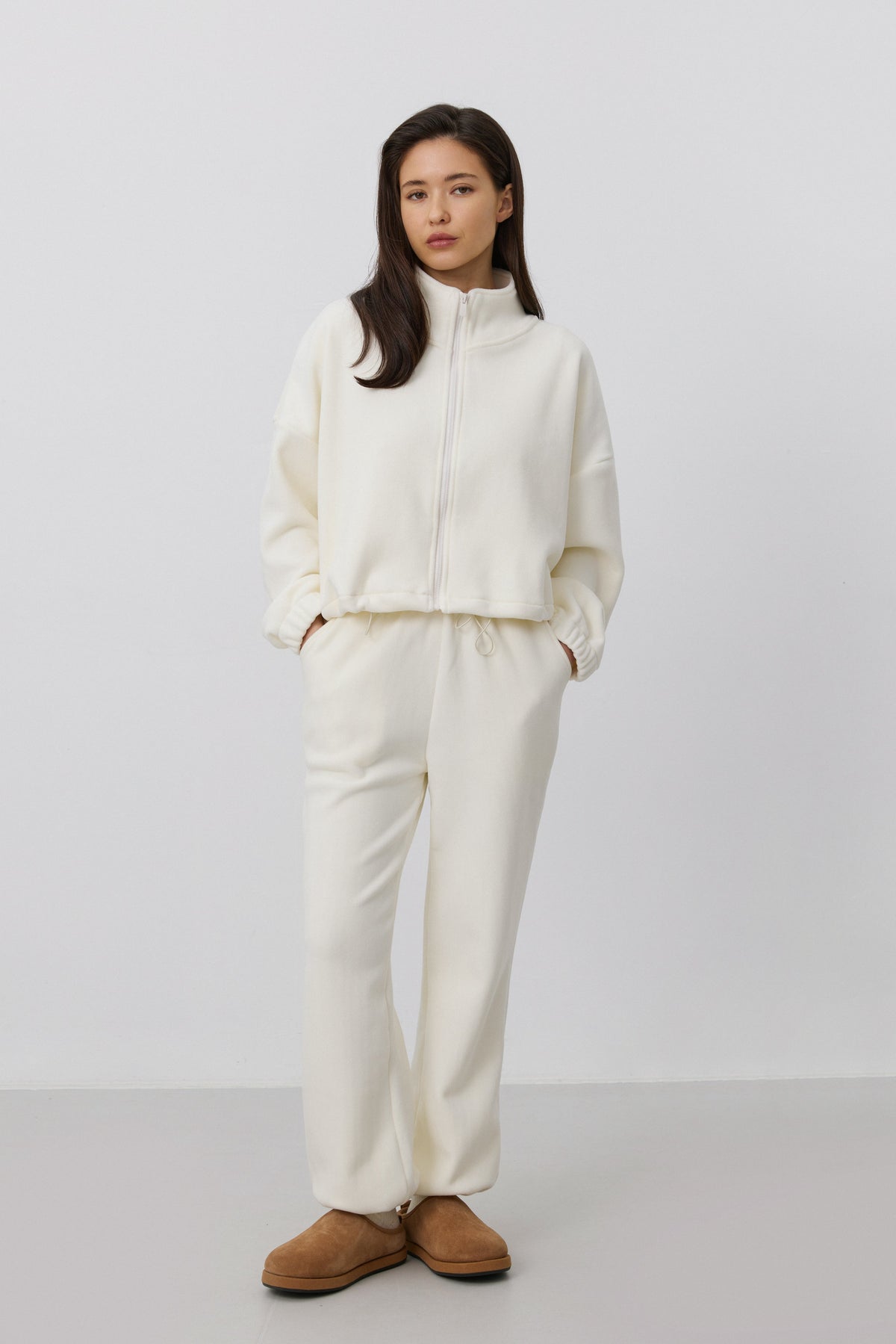 Frontalansicht des Models im hellbeigen Damen-Fleece-Set mit entspanntem Loose Fit und braunen Hausschuhen
