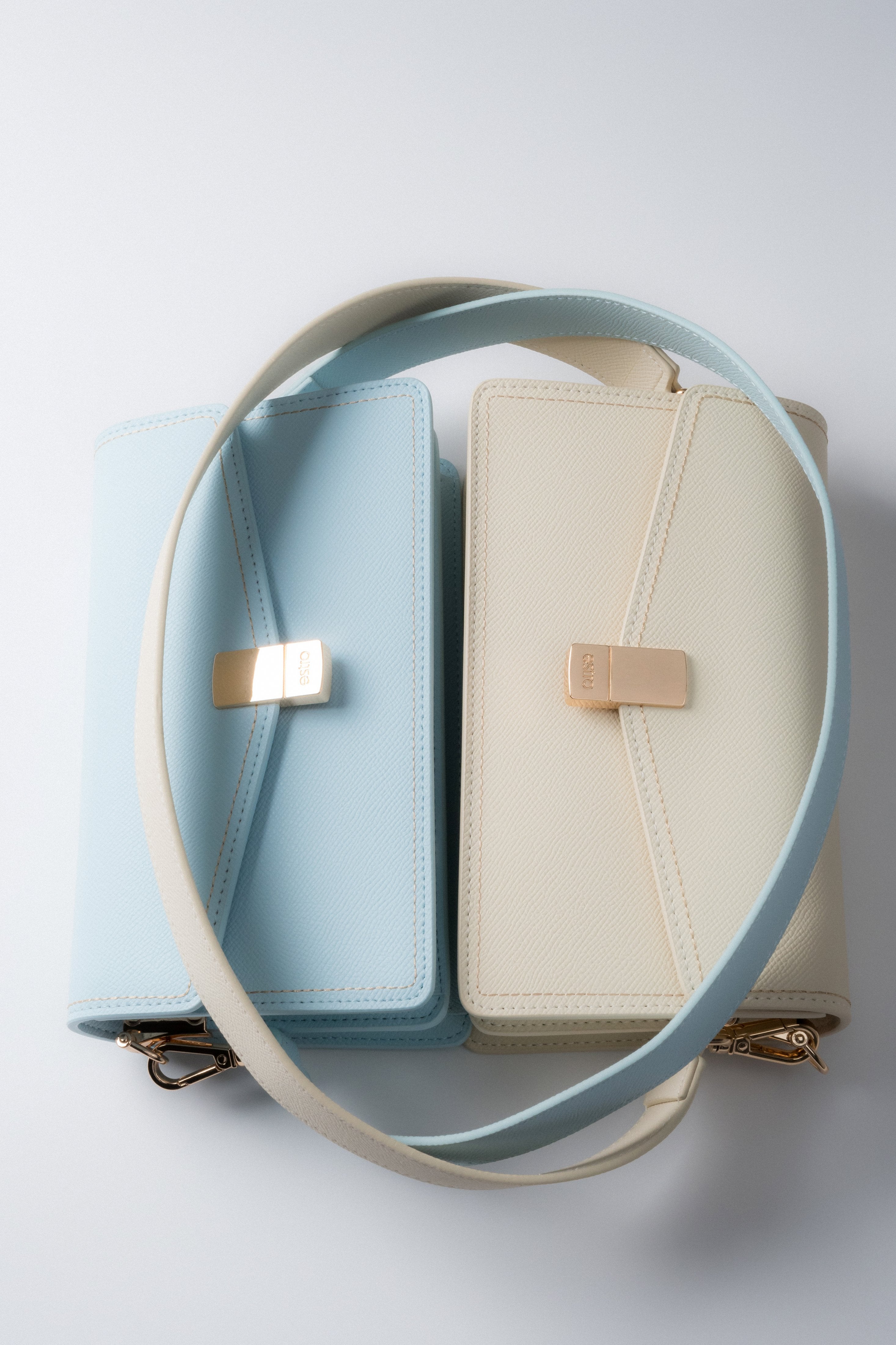 Hellblaue und milchbeige Damenhandtaschen aus Leder mit langem Schulterriemen.