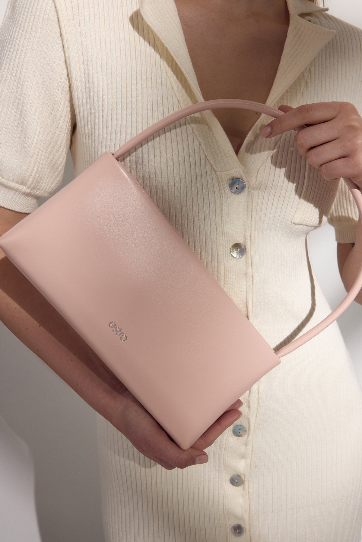 Elegante hellrosa Schultertasche, präsentiert von einem Modell.