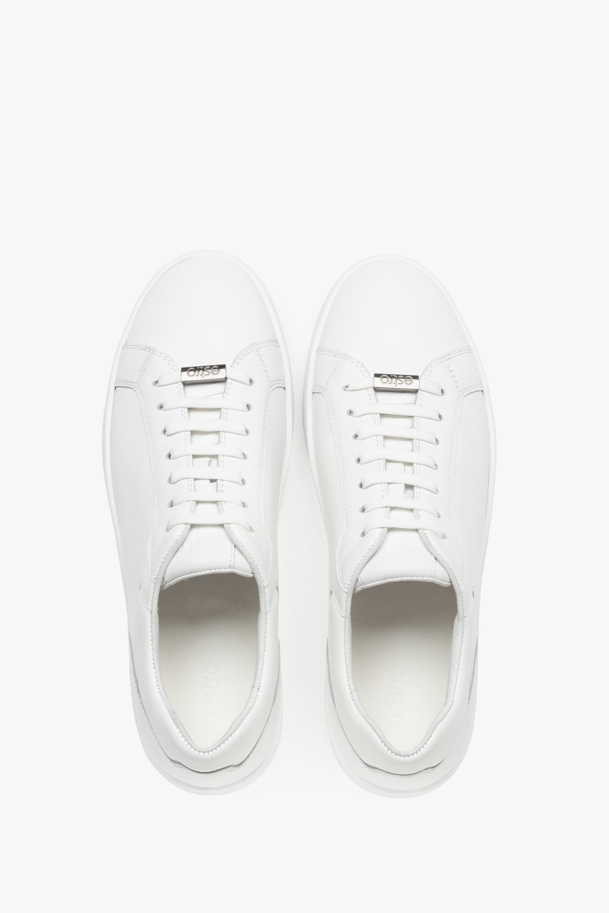 Draufsicht auf das Paar weißer Sneaker mit Logo-Emblem an der Schnürung.