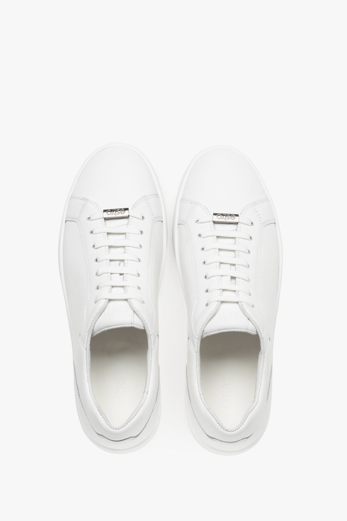 Draufsicht auf das Paar weißer Sneaker mit Logo-Emblem an der Schnürung.