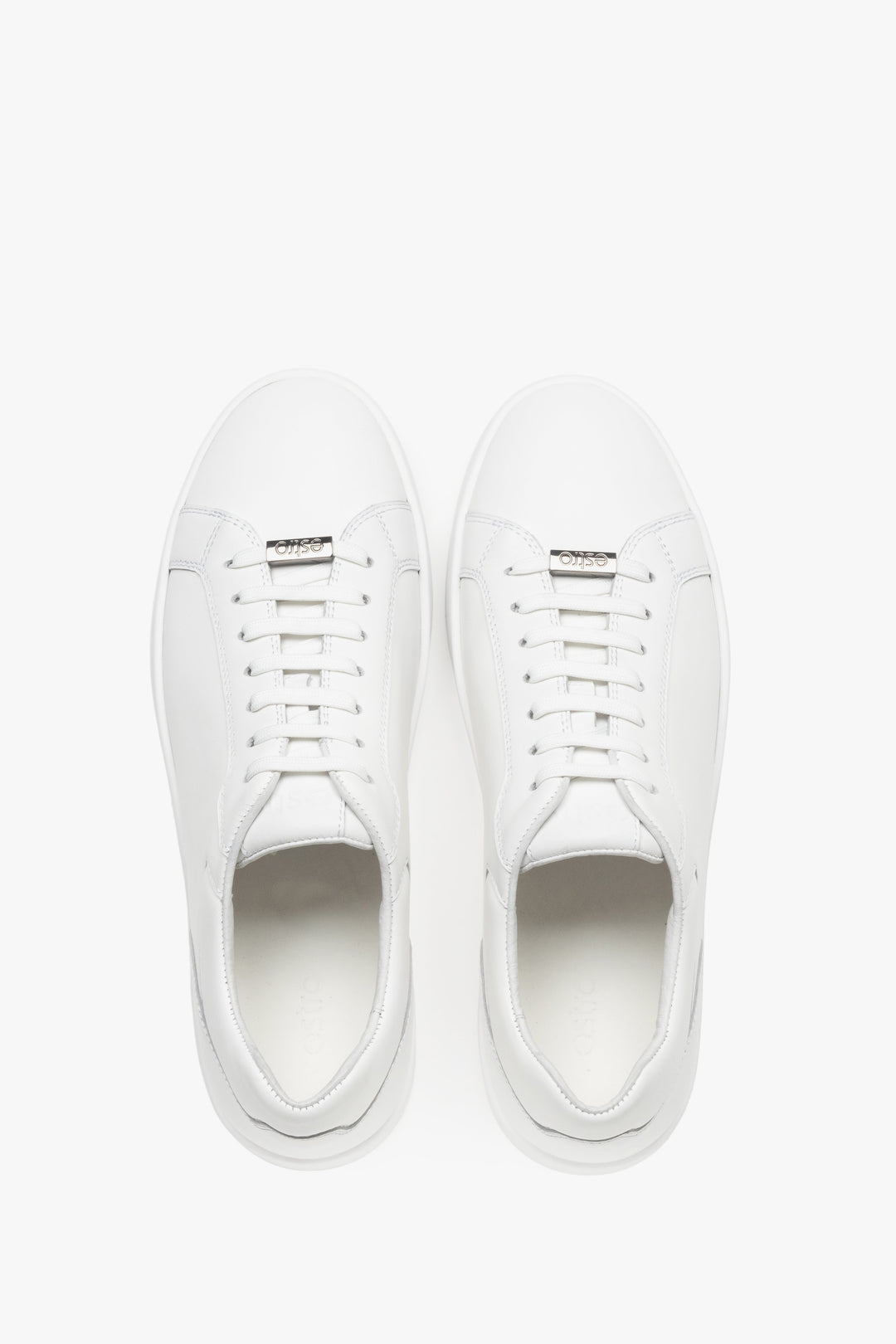 Draufsicht auf das Paar weißer Sneaker mit Logo-Emblem an der Schnürung.