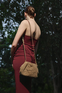 Das Model präsentiert die beige Estro Beuteltasche aus Veloursleder als elegante Schultertasche.