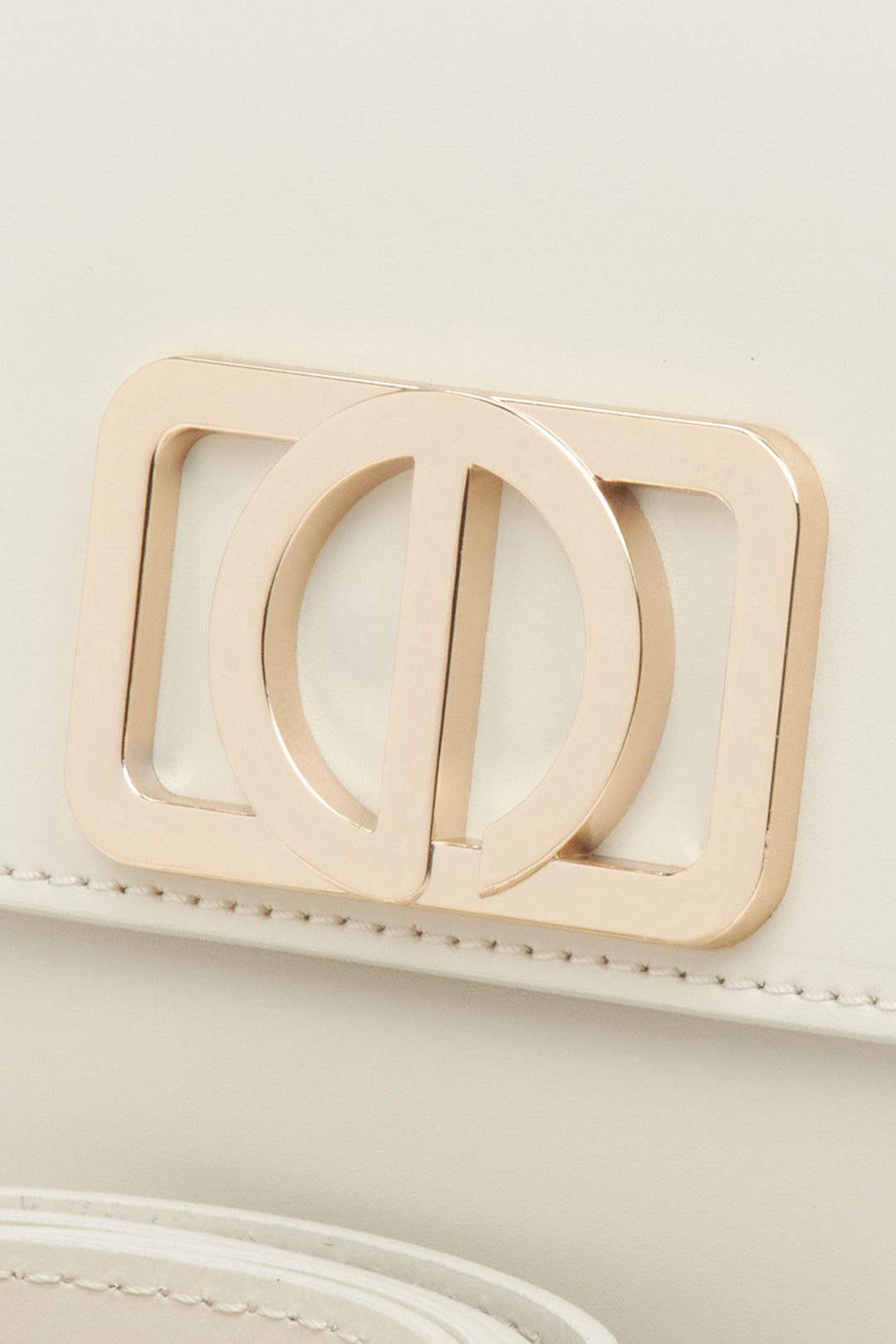 Damenhandtasche in milchigem Beige, kompakte Größe, im Baguette-Stil – Nahaufnahme eines Details.