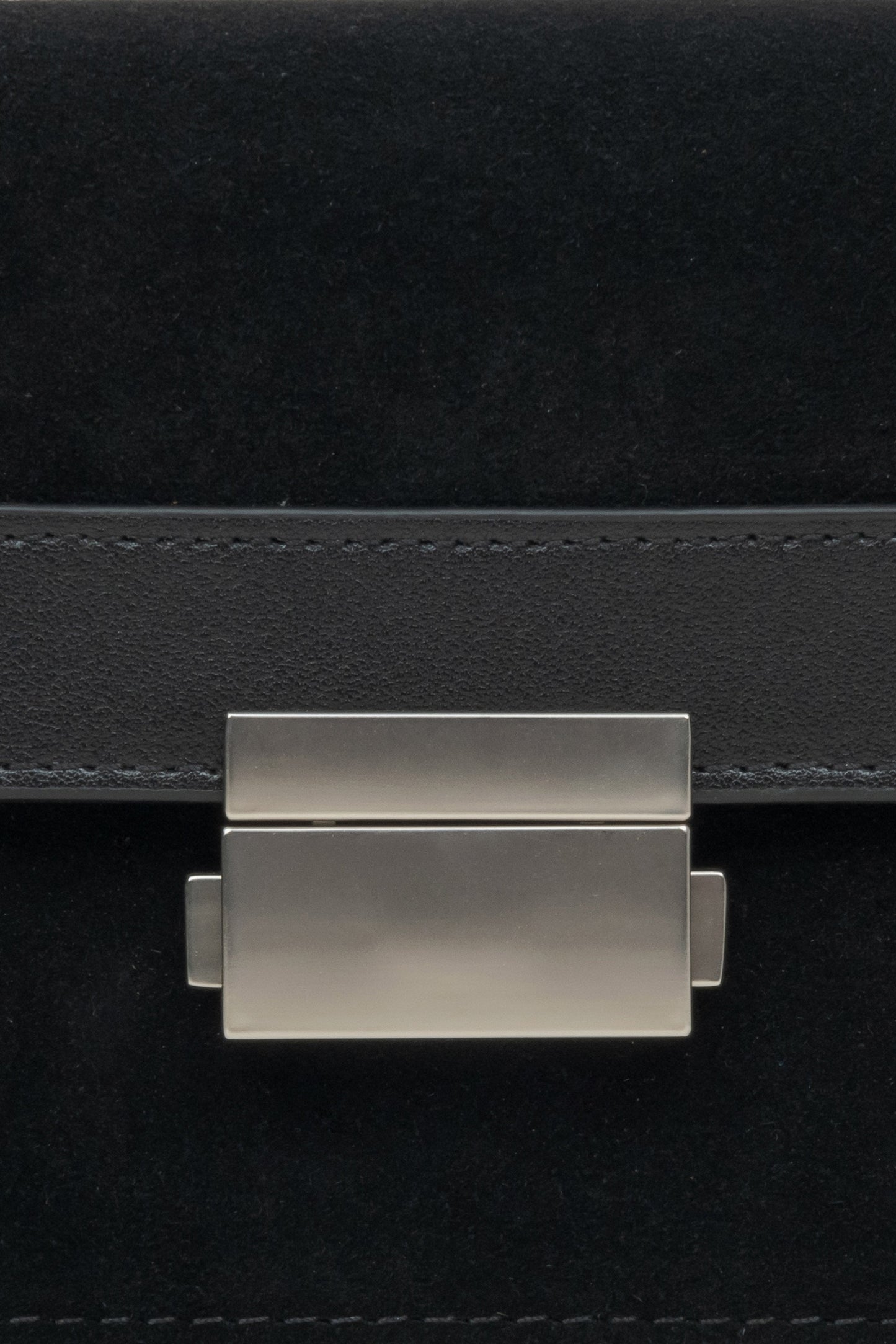 Kompakte Damenhandtasche aus Leder und Velours in Schwarz – Nahaufnahme eines Details.