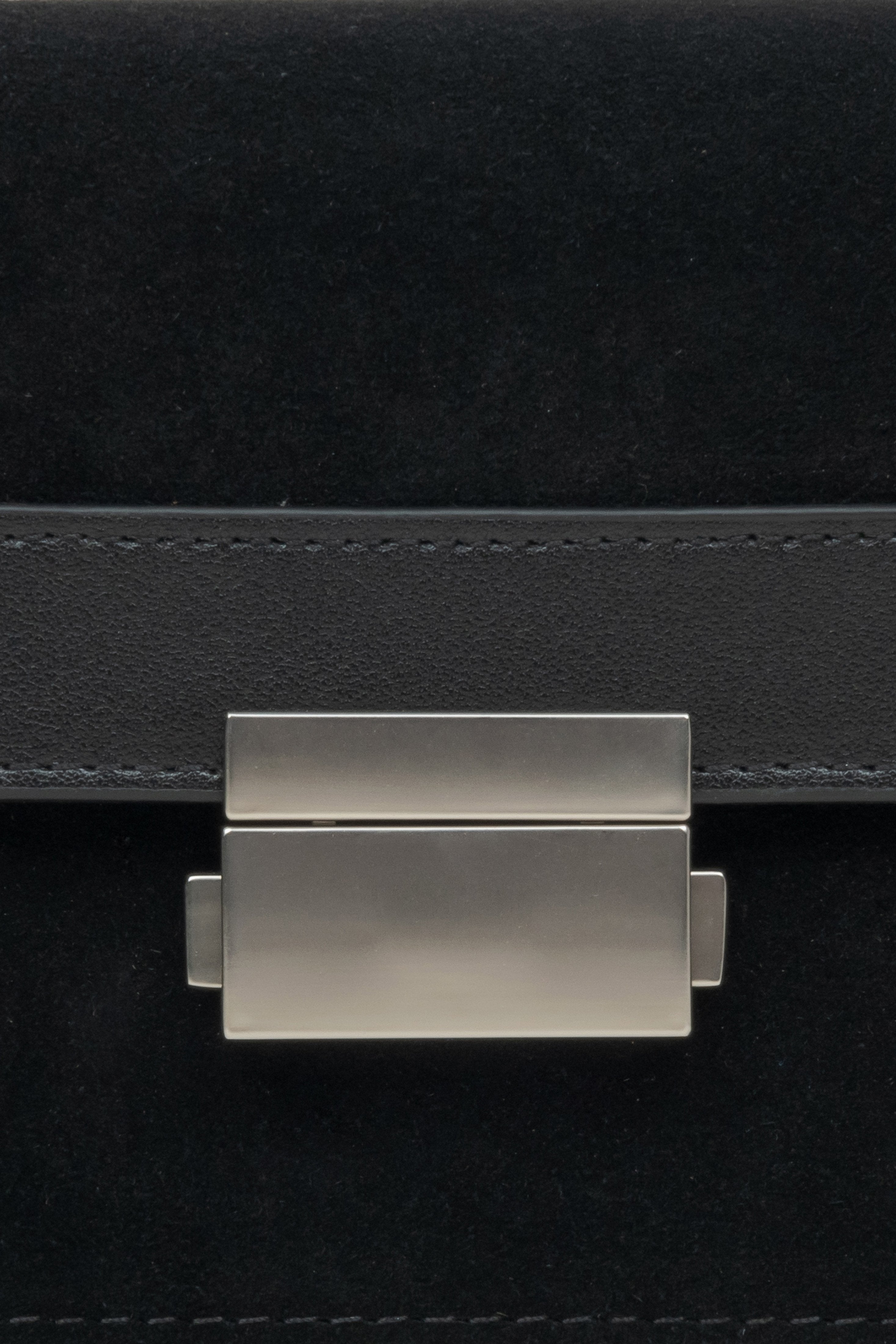 Kompakte Damenhandtasche aus Leder und Velours in Schwarz – Nahaufnahme eines Details.