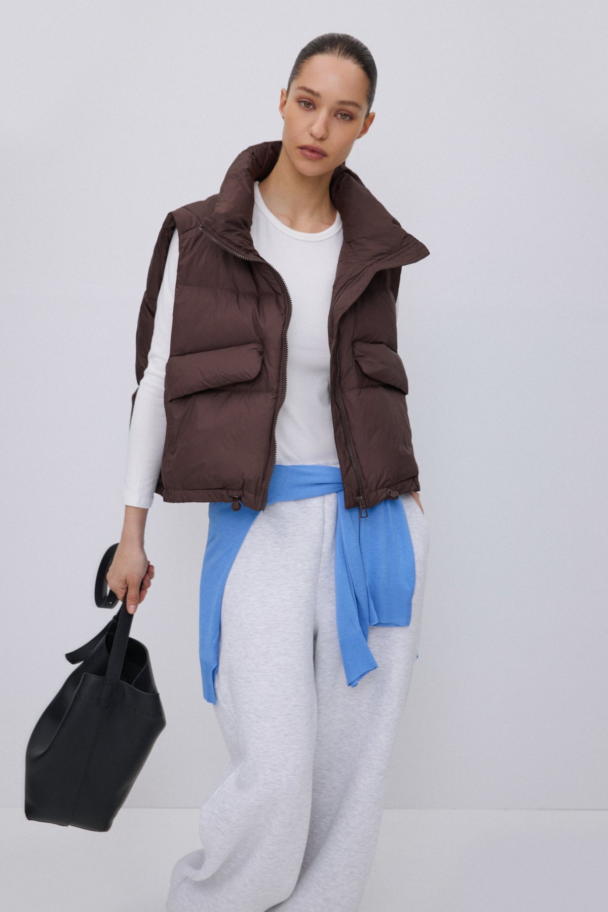 Dunkelbraune Damen Daunenweste mit hohem Kragen präsentiert am Model.