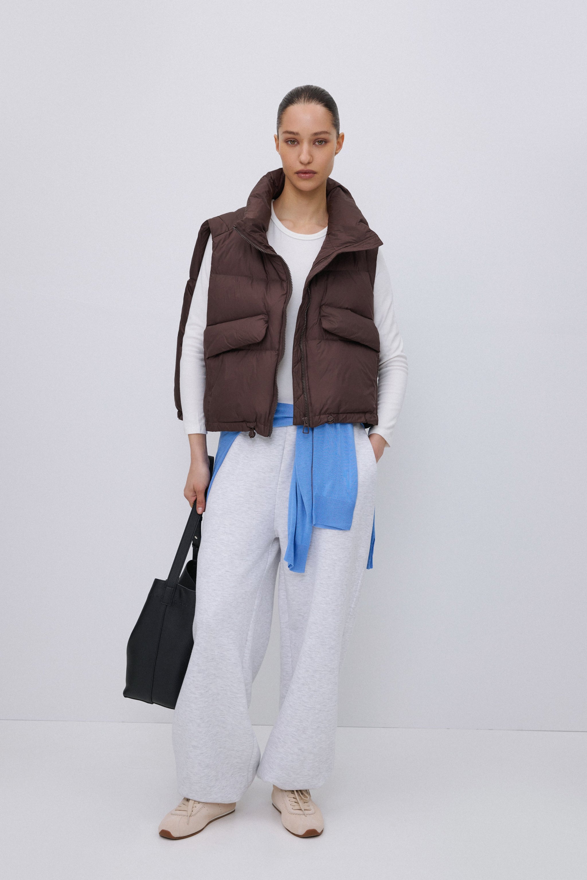 Frontansicht der kurzen dunkelbraunen Damen Daunenweste mit hohem Kragen  - Lifestyle Outfit