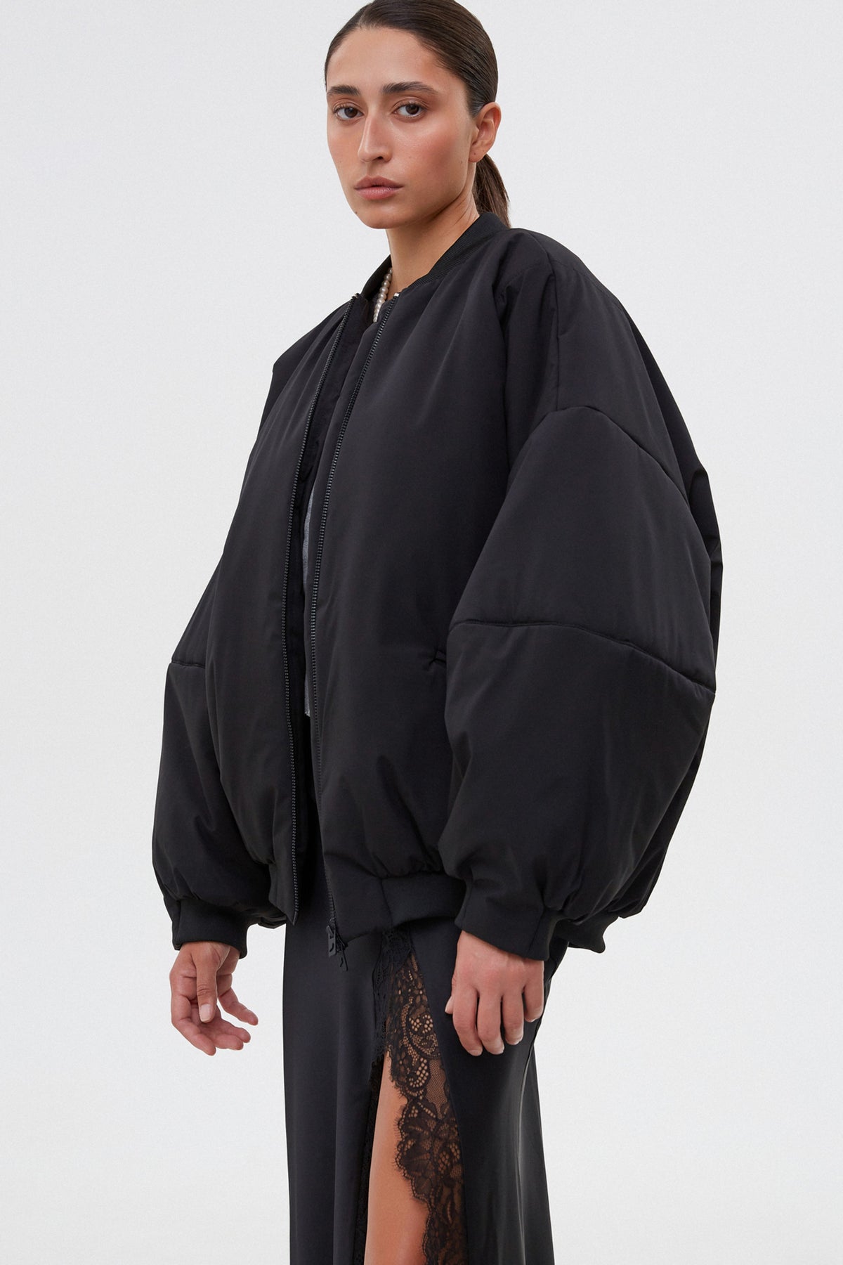 Profilansicht der schwarzen Bomberjacke mit voluminösen Ärmeln.