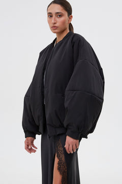 Profilansicht der schwarzen Bomberjacke mit voluminösen Ärmeln.