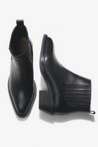Künstlerische Draufsicht auf das Paar der kurzen schwarzen Cowboystiefel aus Echtleder