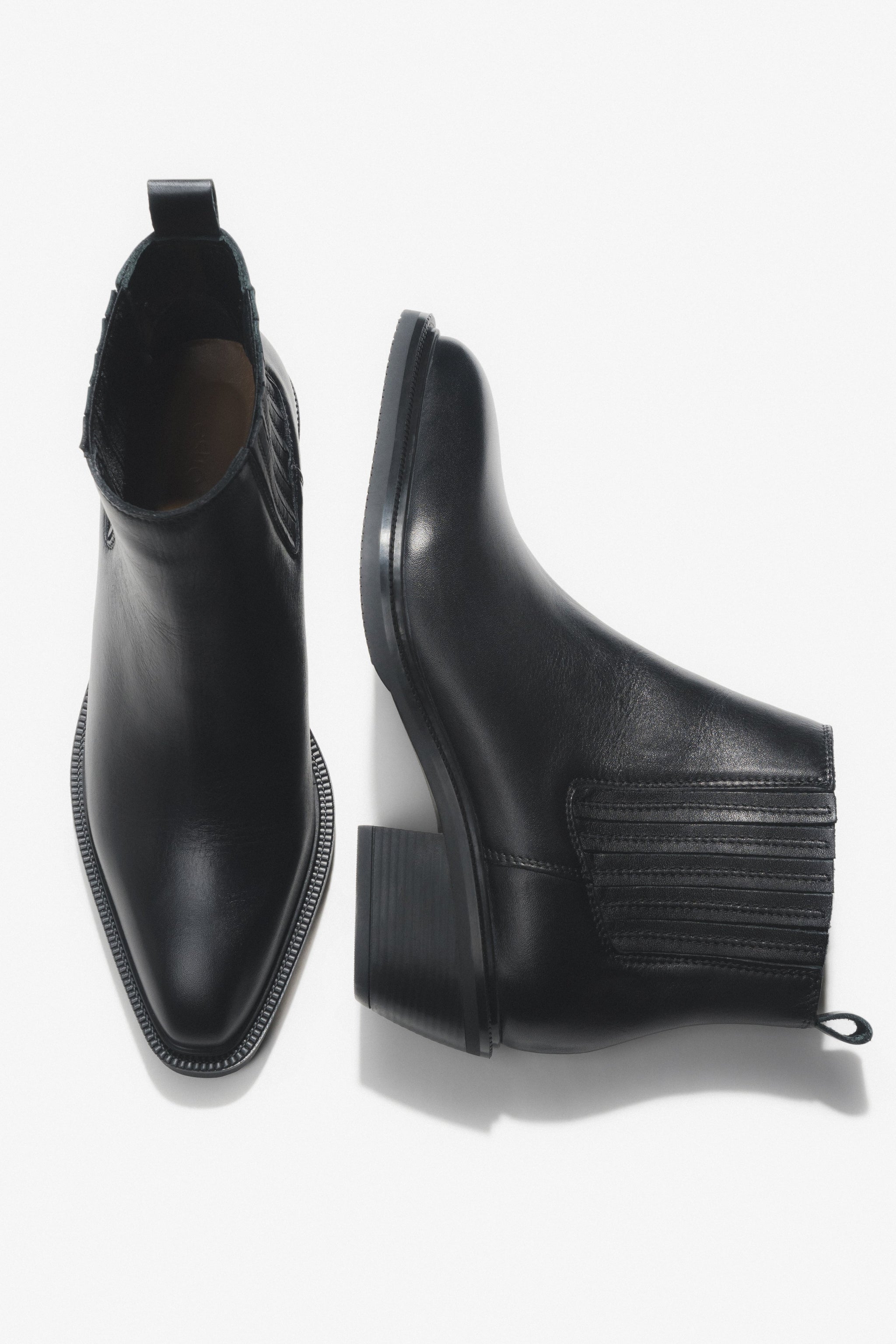 Künstlerische Draufsicht auf das Paar der kurzen schwarzen Cowboystiefel aus Echtleder
