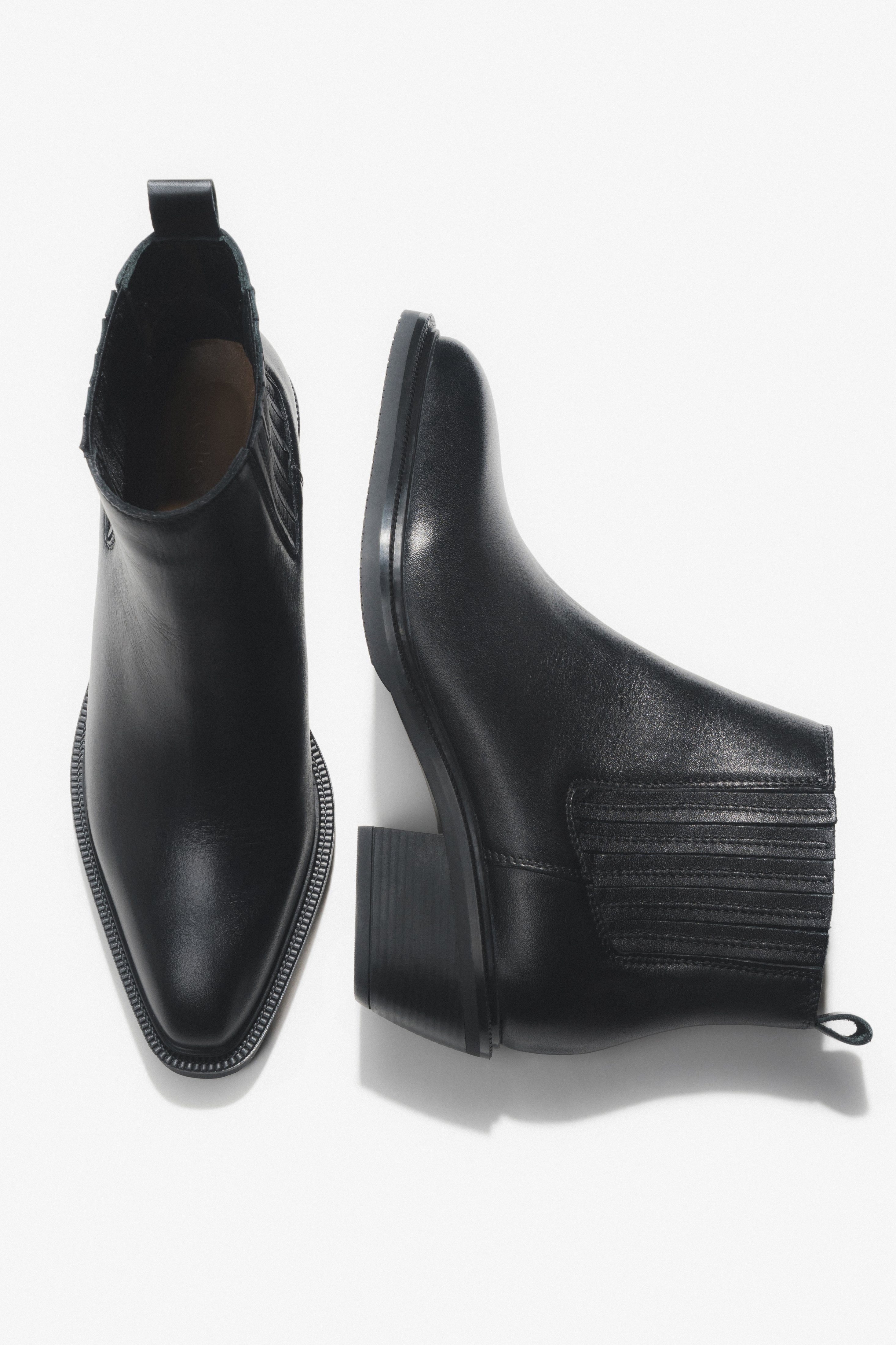 Künstlerische Draufsicht auf das Paar der kurzen schwarzen Cowboystiefel aus Echtleder