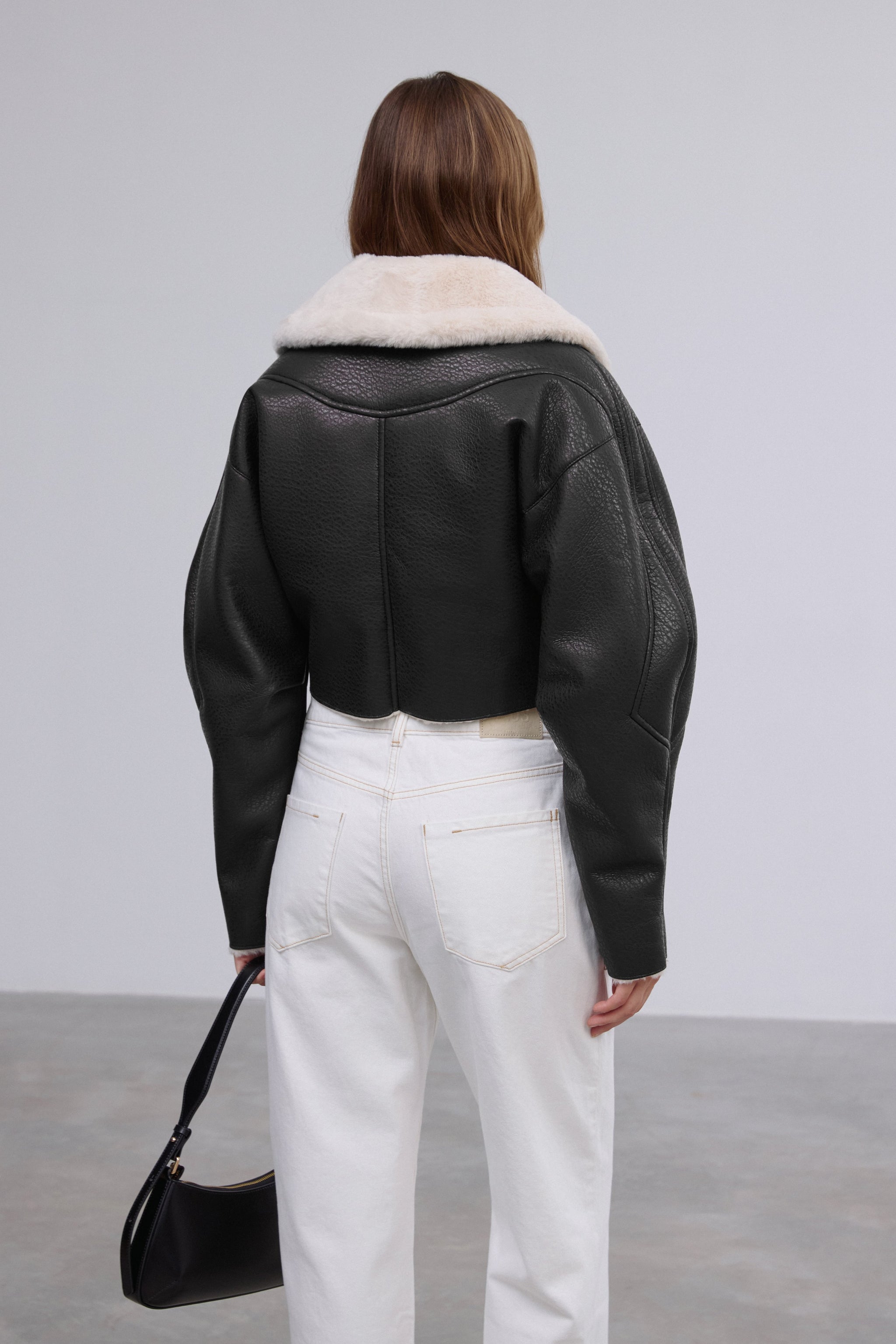 Rückansicht der schwarzen Faux-Shearling-Jacke, die die strukturierte Passform präsentiert 