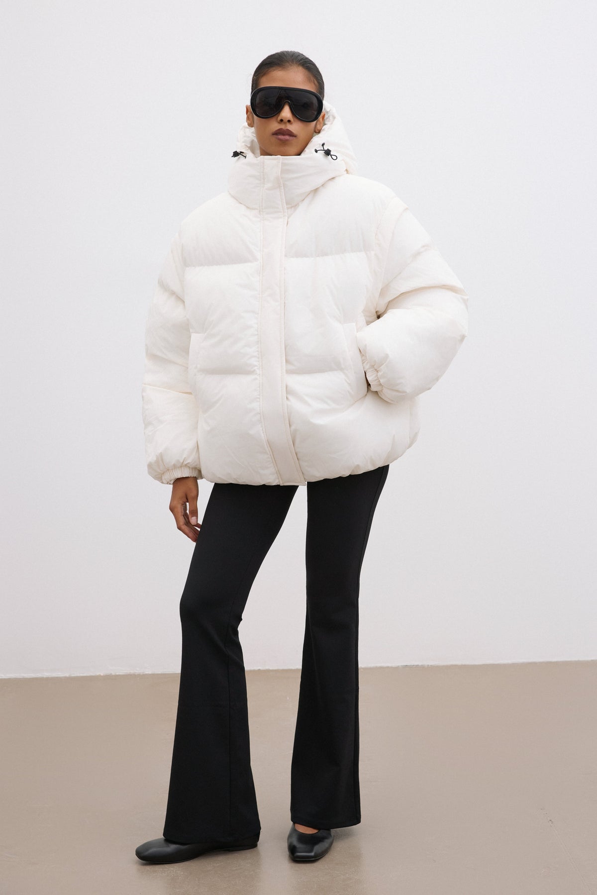 Ganzkörperansicht des Models in der milchbeigen Oversize-Winterjacke von vorne 