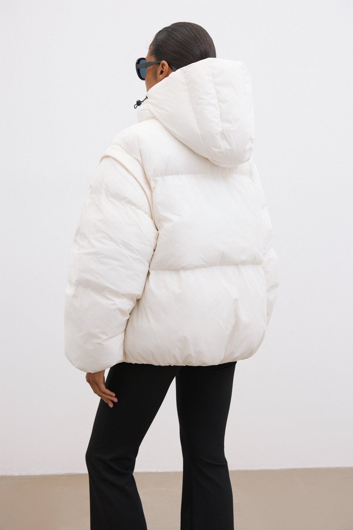 Rückansicht der milchbeigen Steppjacke, die die voluminöse Passform und die Kapuze zeigt 