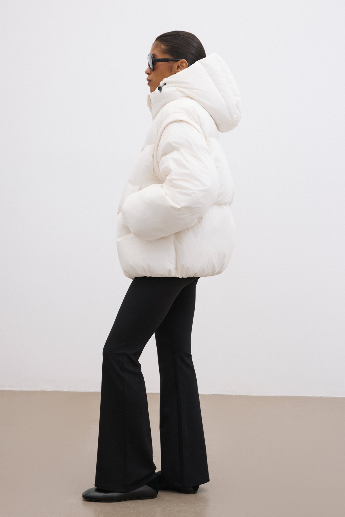 Seitenprofil des milchbeigen Daunen-Modells mit Fokus auf den Oversize-Schnitt und die Taschen 