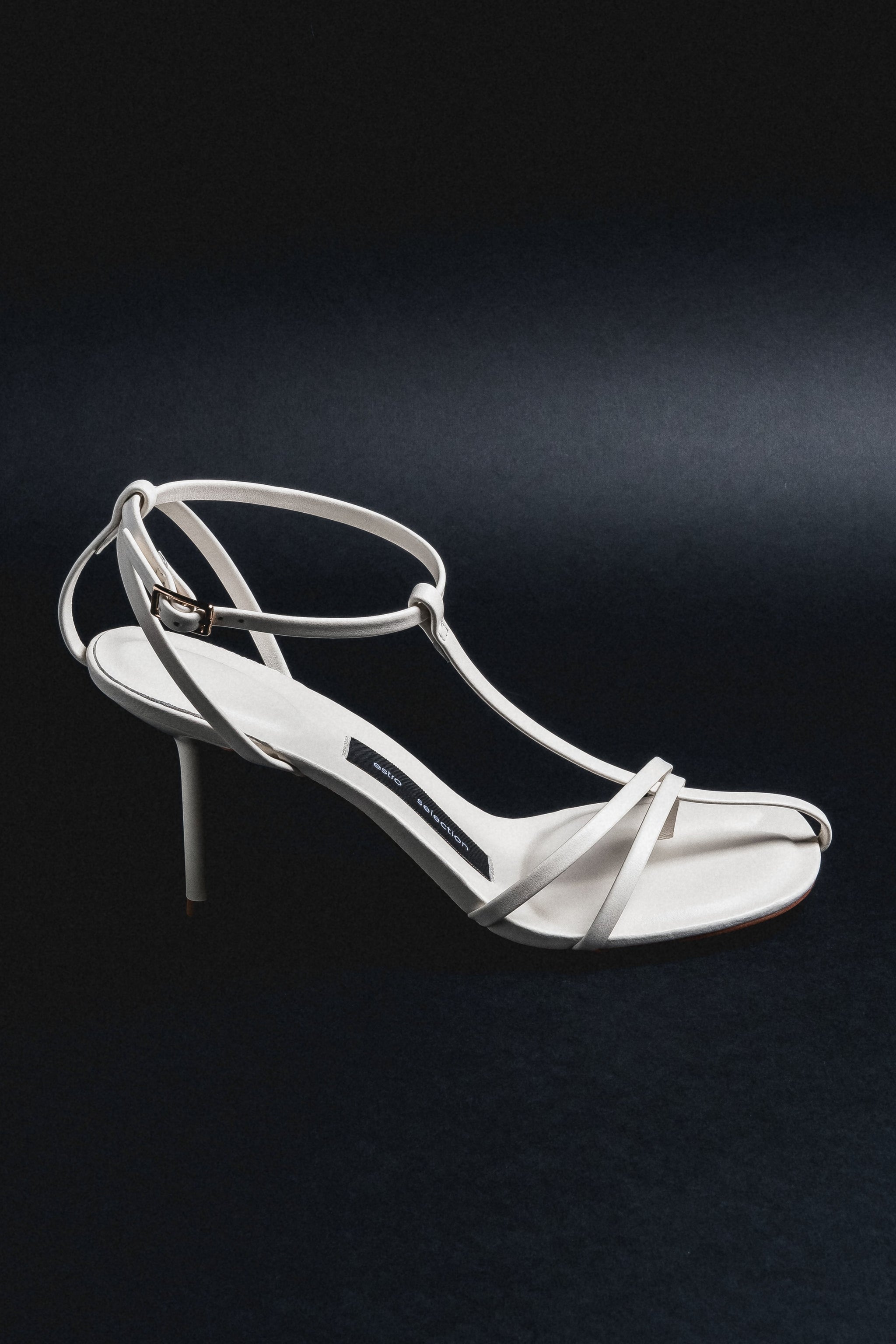 Milchbeige Damen-Sandalette aus Echtleder in schräger Ansicht auf schwarzem Hintergrund
