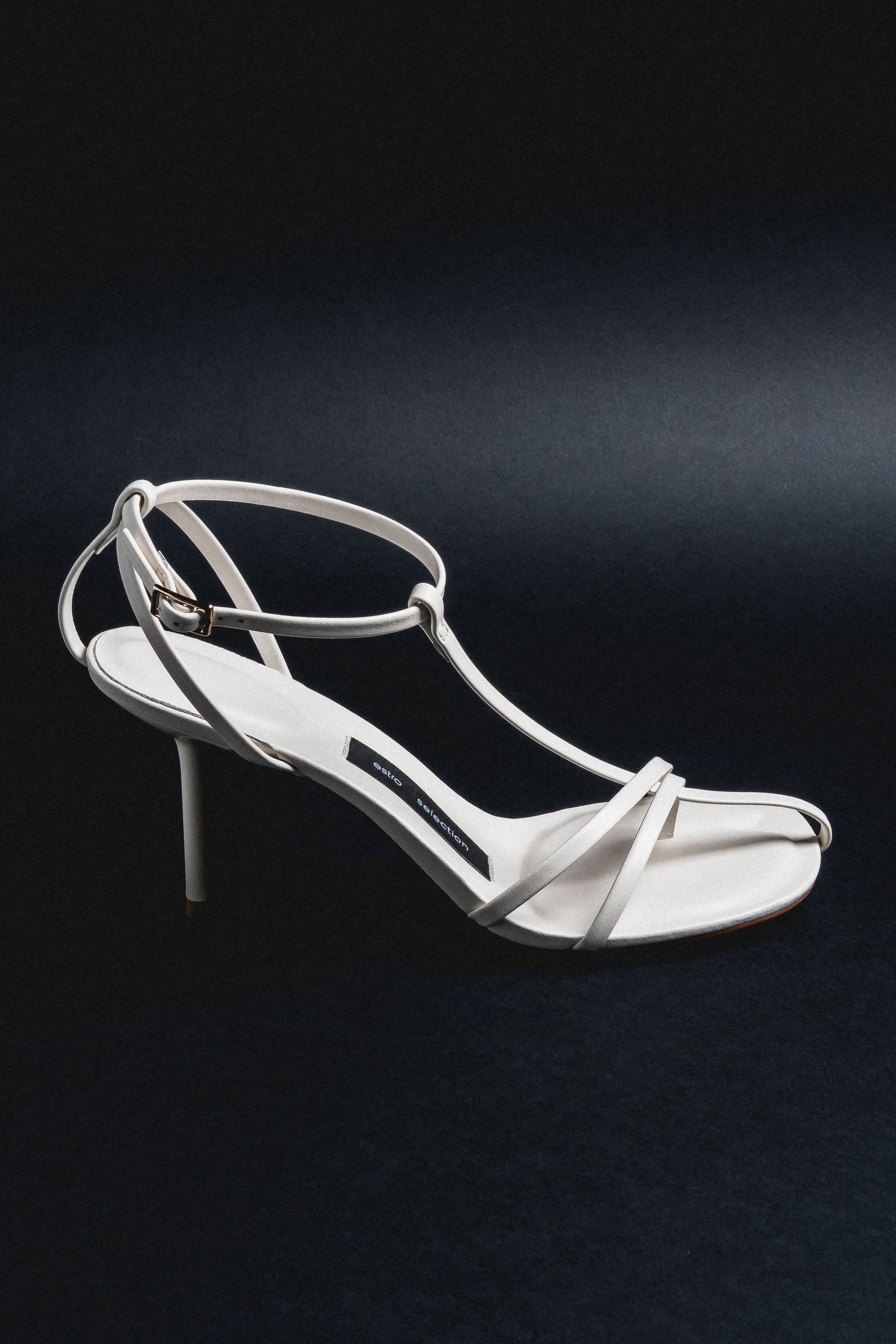Milchbeige Damen-Sandalette aus Echtleder in schräger Ansicht auf schwarzem Hintergrund