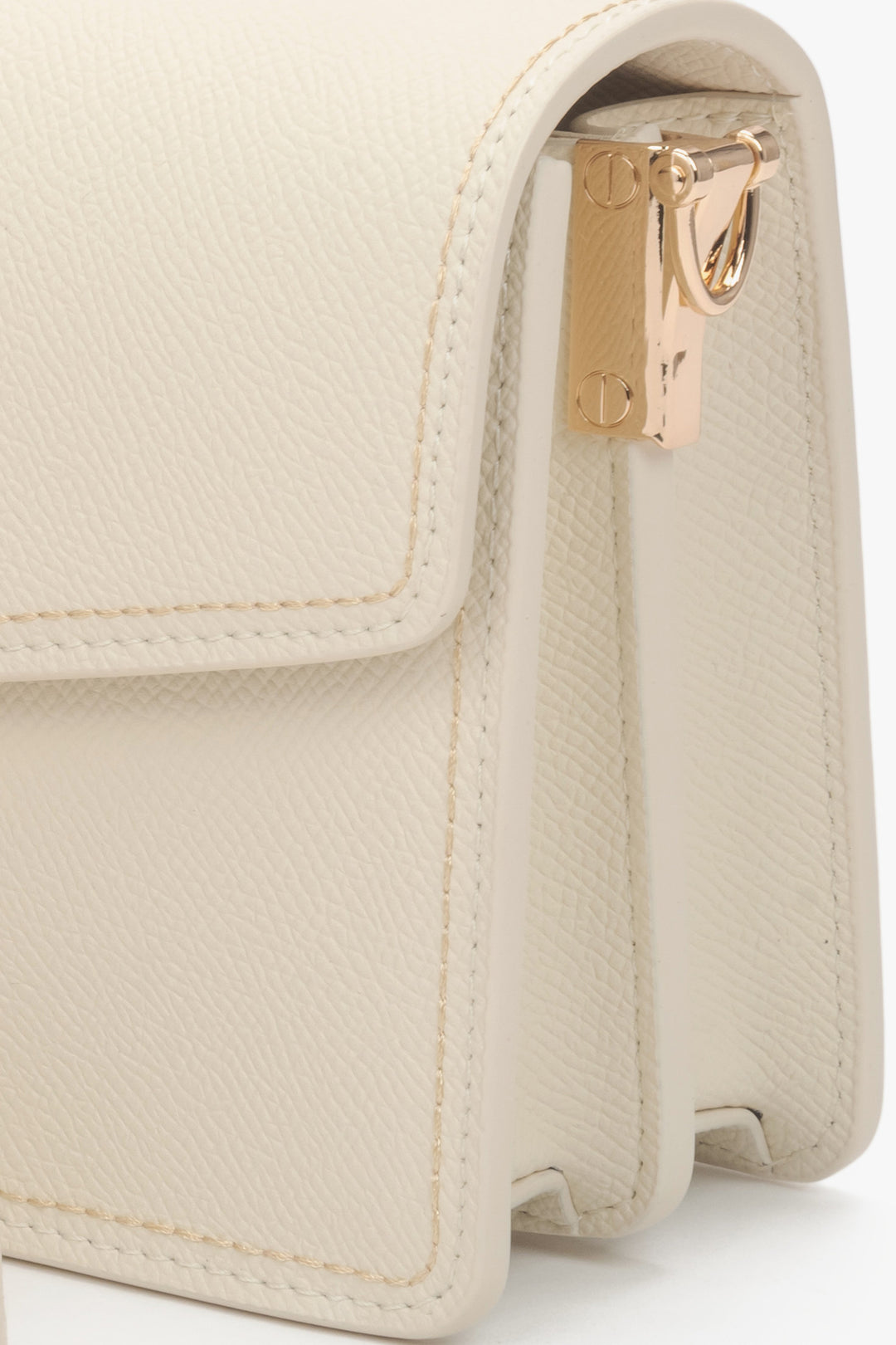 Detailaufnahme der goldenen Beschläge an der hellbeigen Ledertasche.