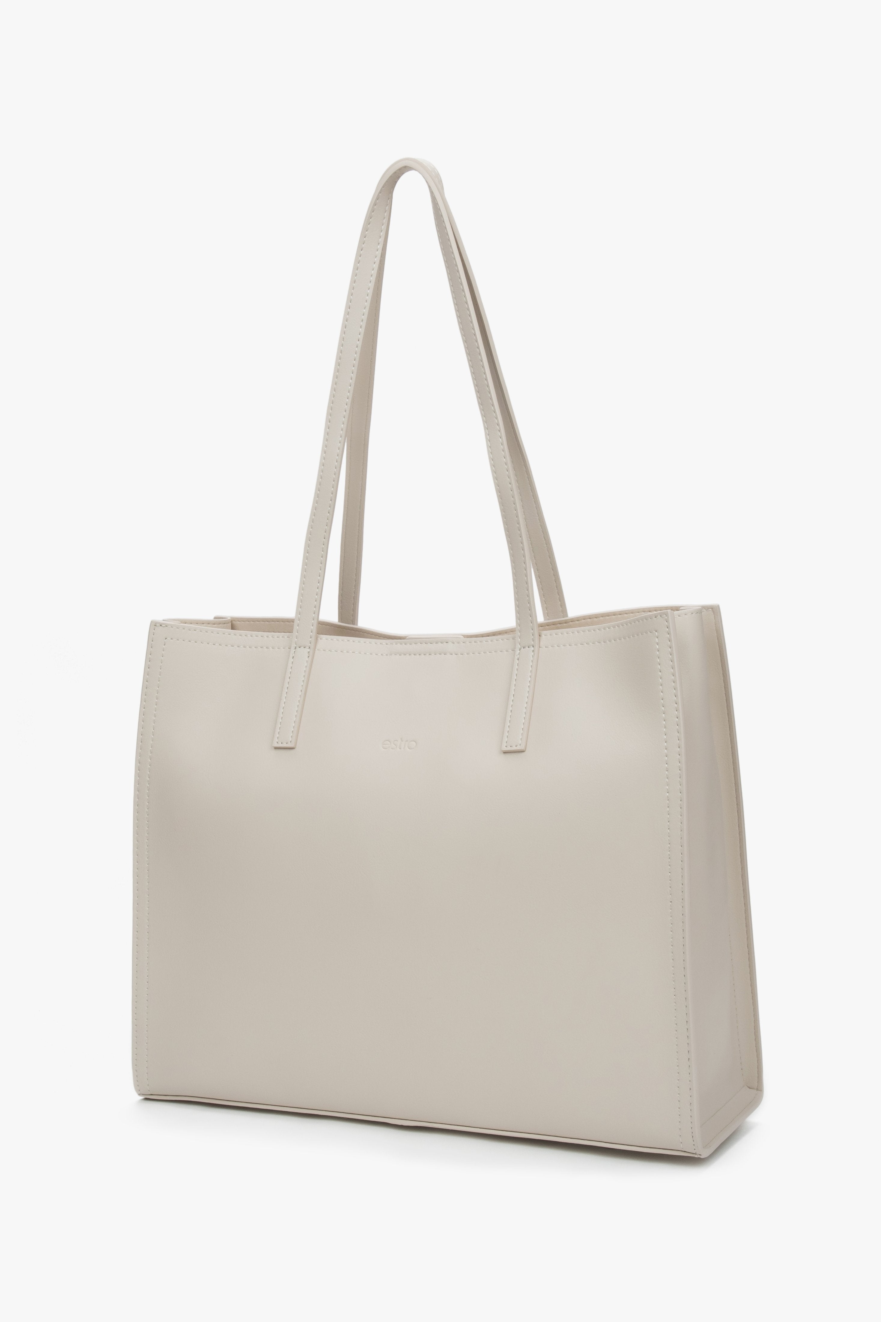 Schräge Seitenansicht der milchbeigen Ledertasche mit Trageriemen.