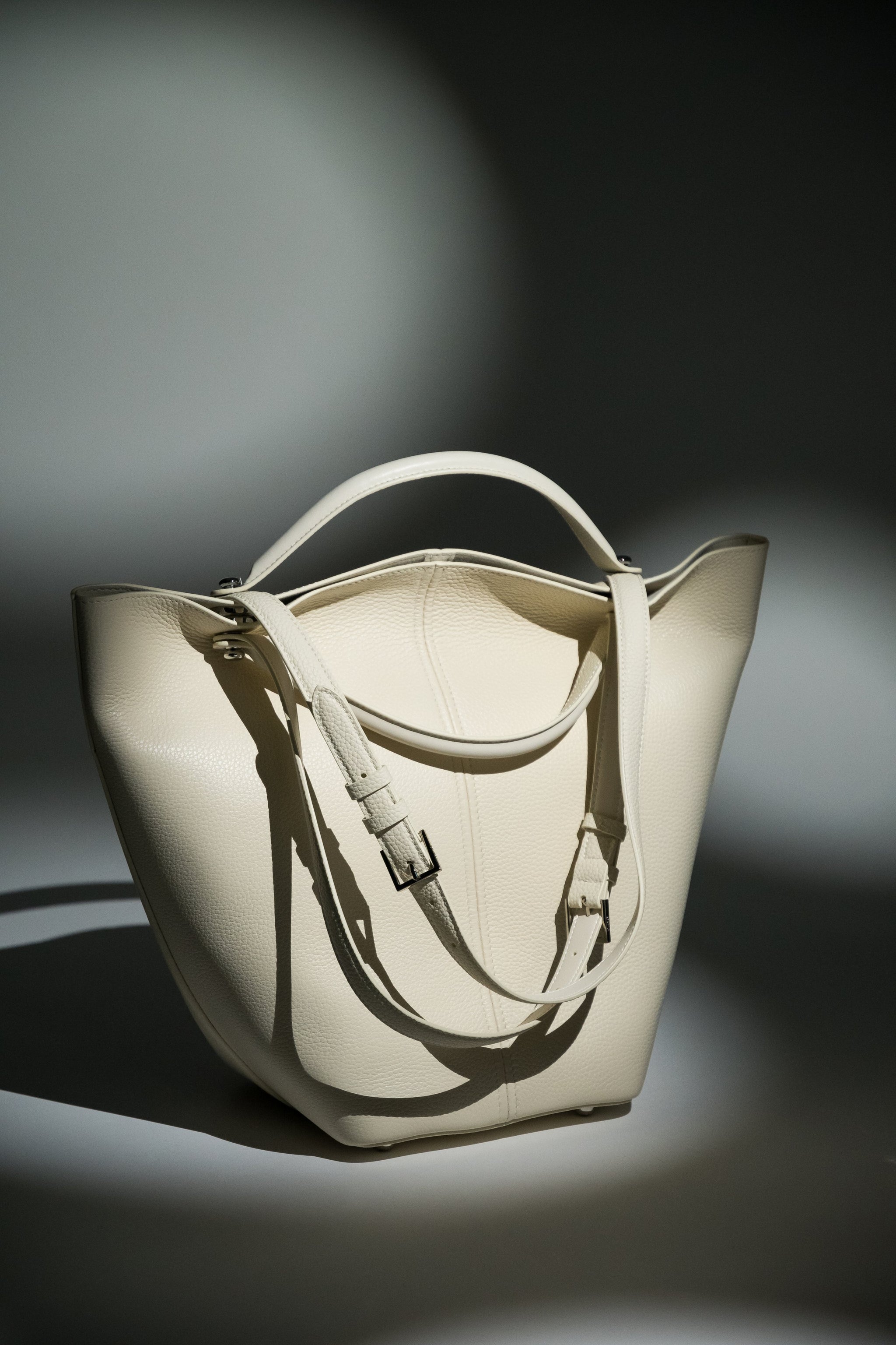 Künstlerische Produktaufnahme der milchbeigen Ledertasche mit dynamischen Schattenwürfen 