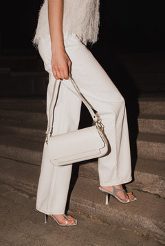 Lifestyle-Aufnahme einer Frau, die die milchbeige Ledertasche elegant auf einer Treppe trägt