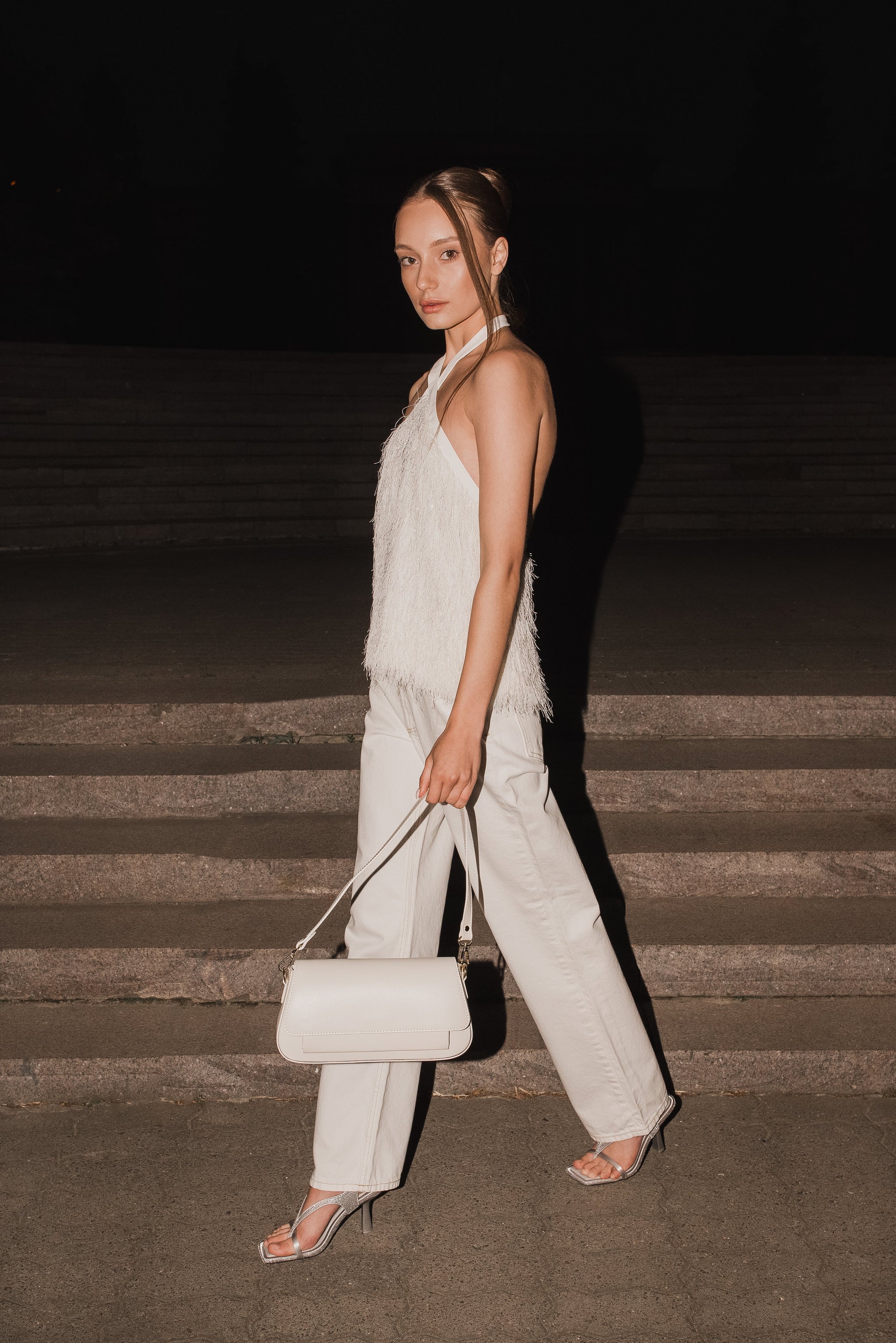 Dynamische Lifestyle-Aufnahme des Models auf einer abendlichen Steintreppe mit der Messenger-Bag