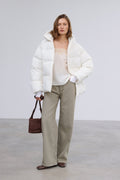 Frontalansicht der milchbeigen Damen-Winterjacke im Loose-Fit, halboffen getragen über einem lässigen Outfit mit dunkler Handtasche