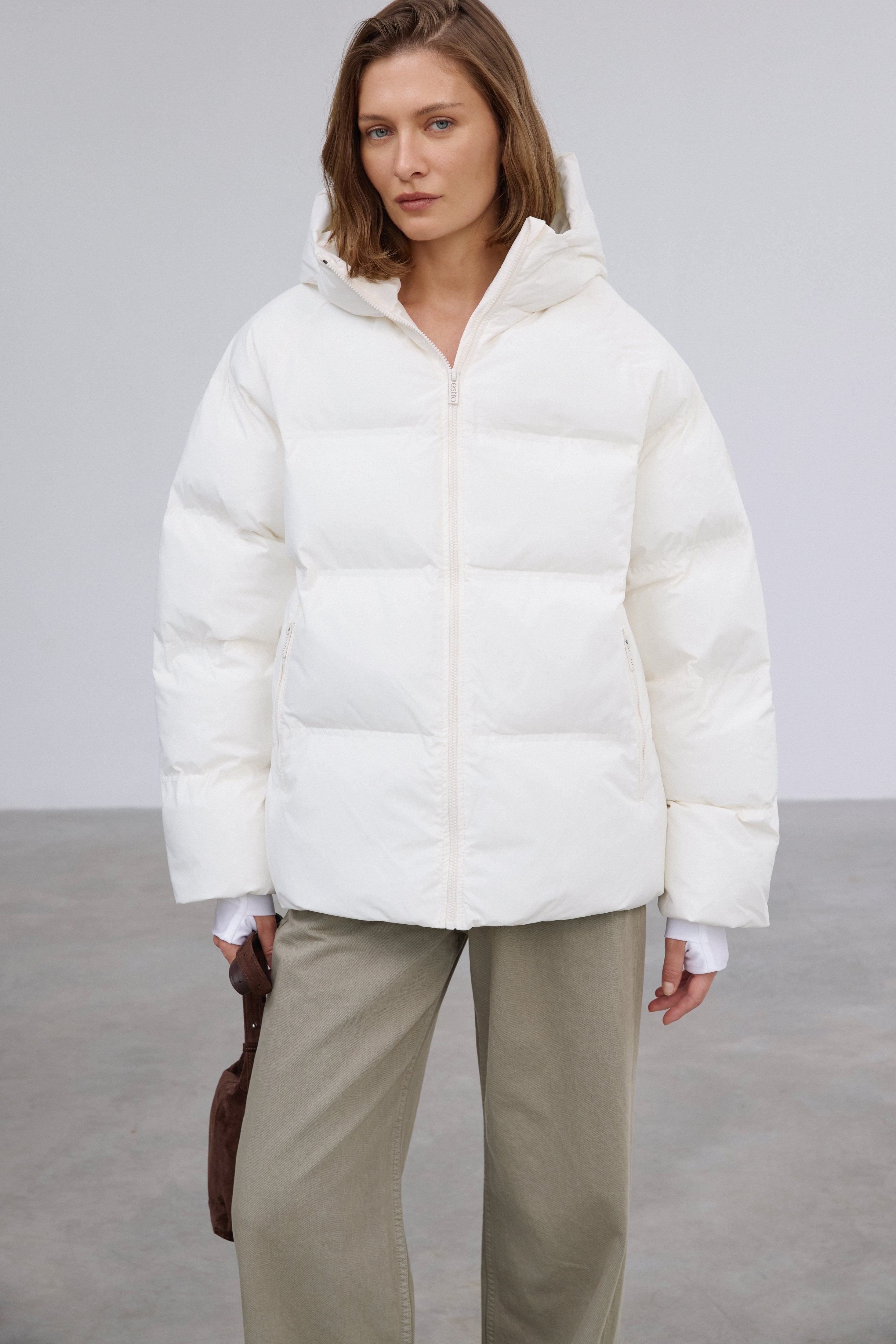 Frontalansicht der milchbeigen Damen-Winterjacke im Loose-Fit, halboffen getragen über einem lässigen Outfit 