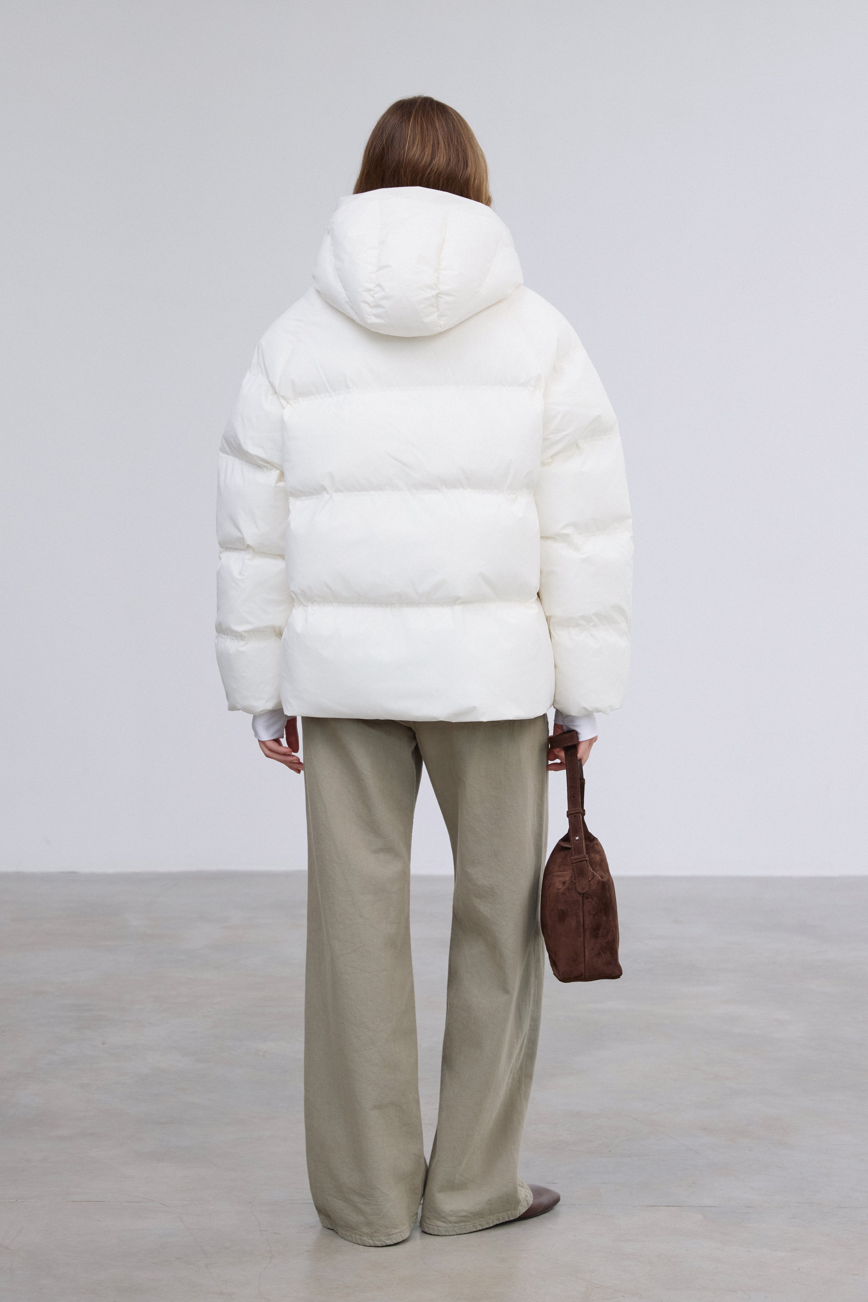 Rückansicht der milchbeigen Oversize-Jacke, die die Länge bis über die Hüfte und die Steppung hervorhebt 