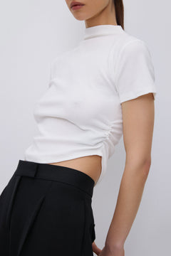 Seitenansicht des T-Shirts, die die asymmetrische Raffung an der Taille deutlich zeigt.