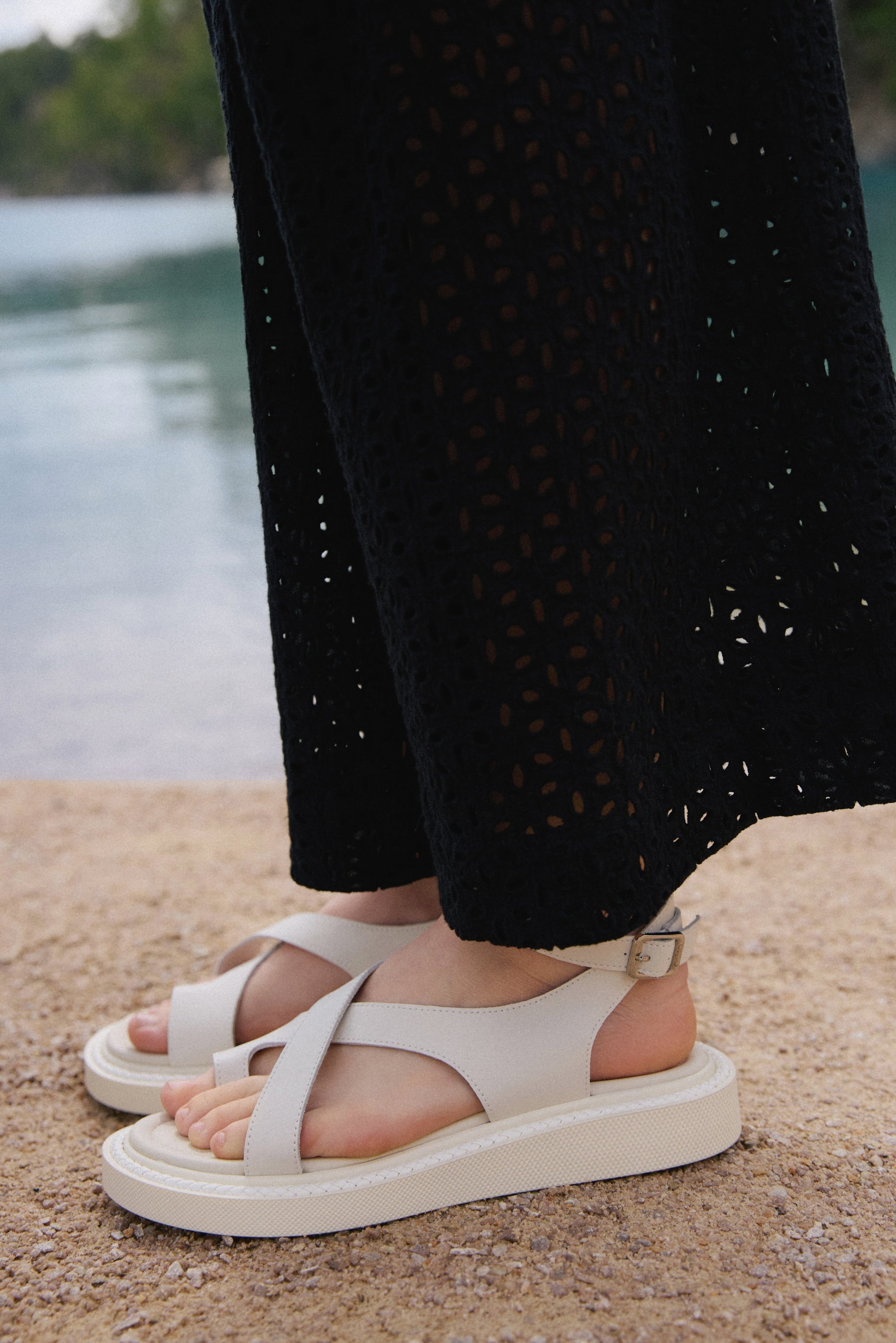 Lifestyle-Ansicht der milchweißen Damen-Sandalen mit Plateausohle am Wasser.