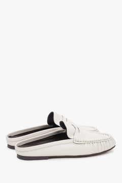 Milchweiße Damen-Mules aus Leder in schräger Seitenansicht mit Loafer-Detail