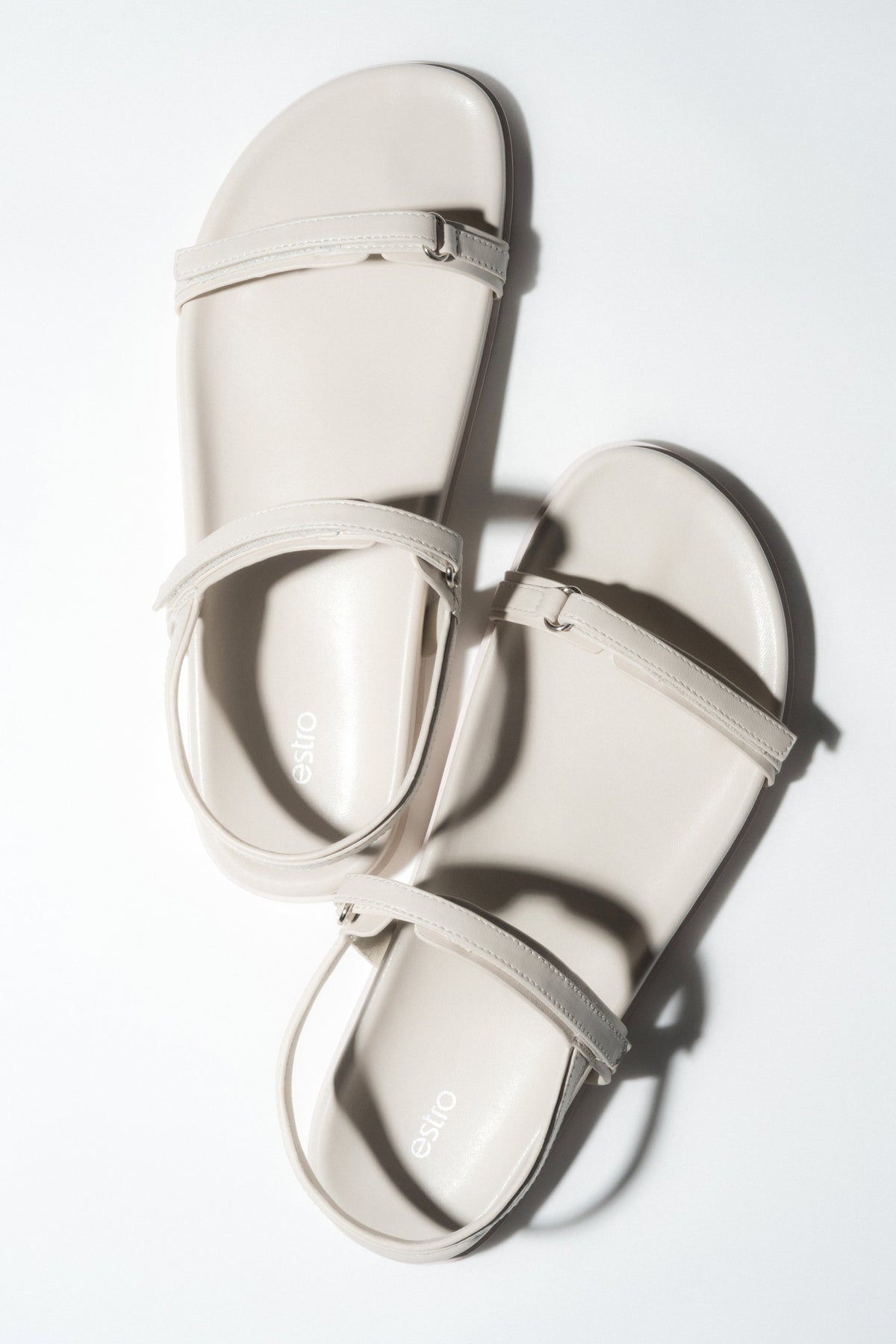 Draufsicht auf das Paar milchweißer Damen-Sandalen aus weichem Echtleder.