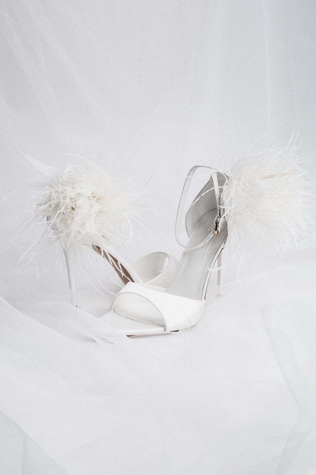 Milchweiße Damen-Sandalette mit Federapplikation in künstlerischer Detailansicht